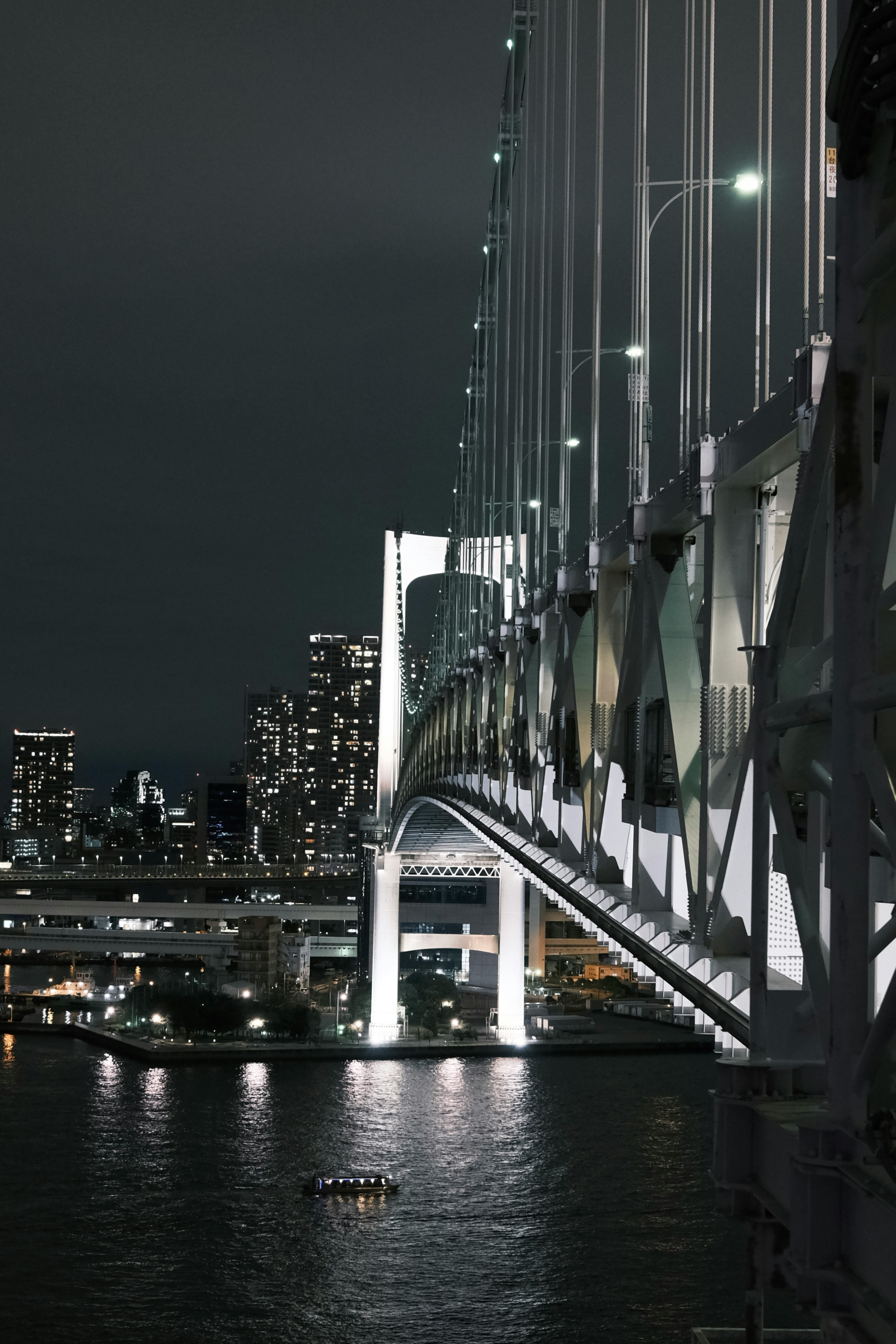 夜の川沿いに並ぶ高層ビルと橋の夜景