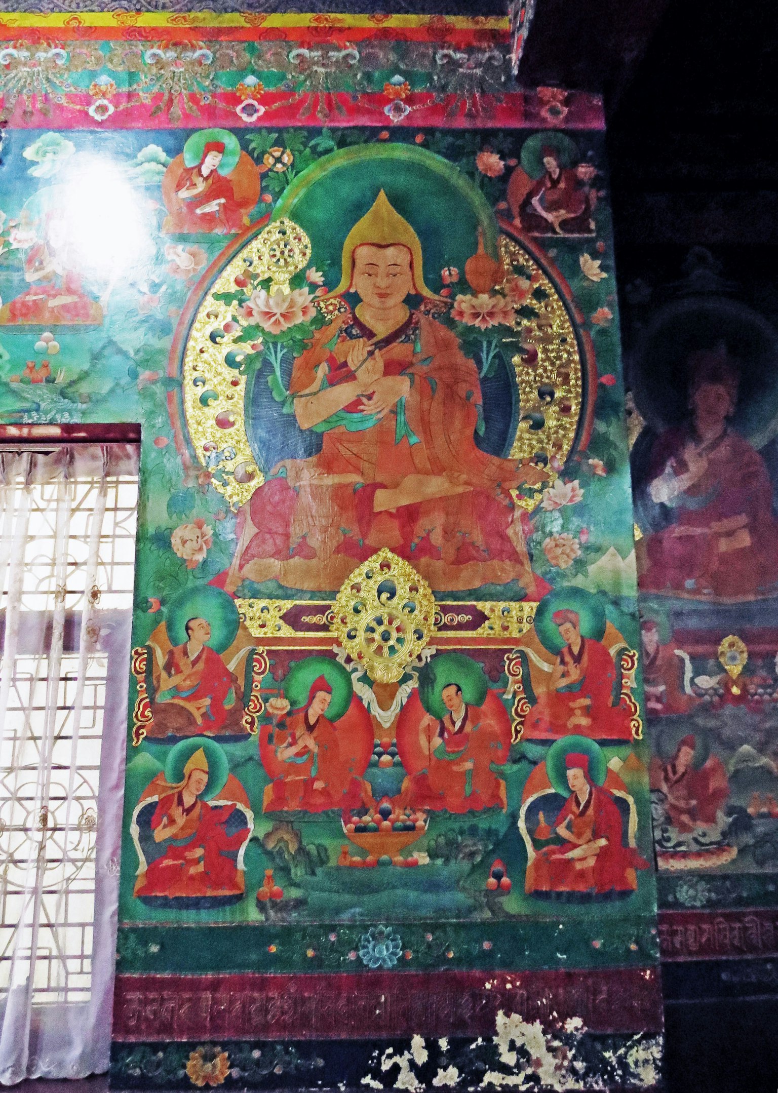 Lebendige buddhistische Wandmalerei, die eine sitzende Figur umgeben von kleineren Figuren in einem Tempel zeigt