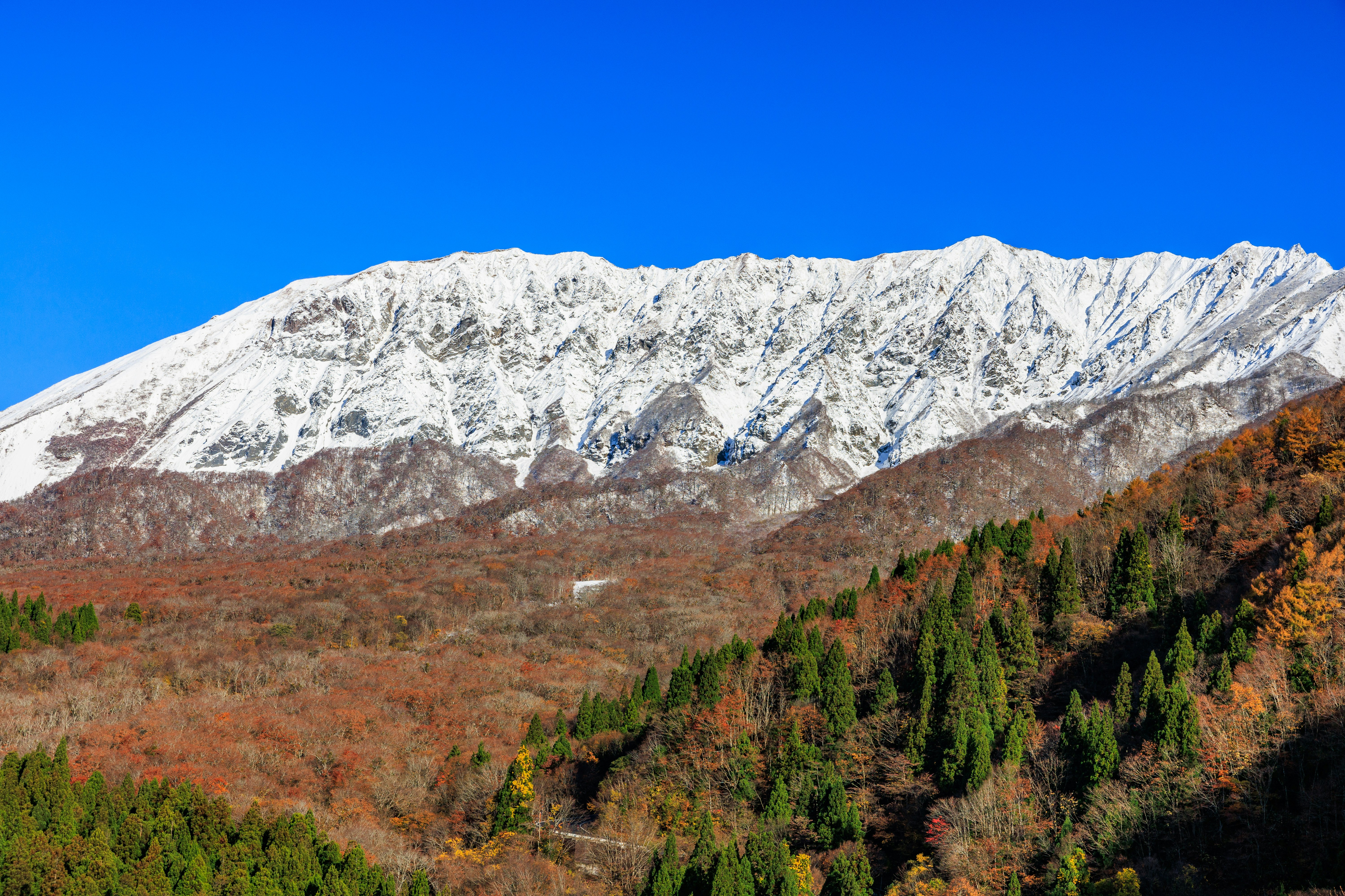 verschneite Berge über einem Herbsttal