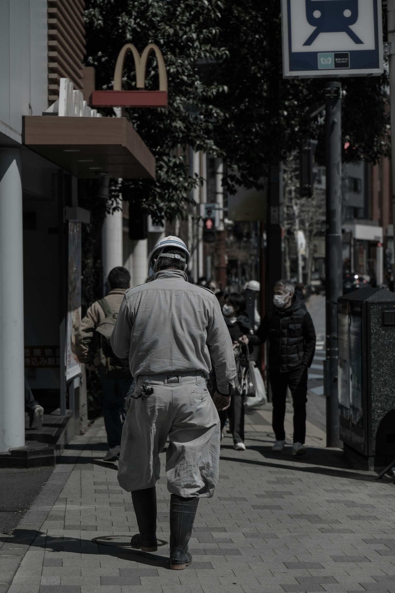 Man in work clothes walking down the street McDonald's sign visible in the background