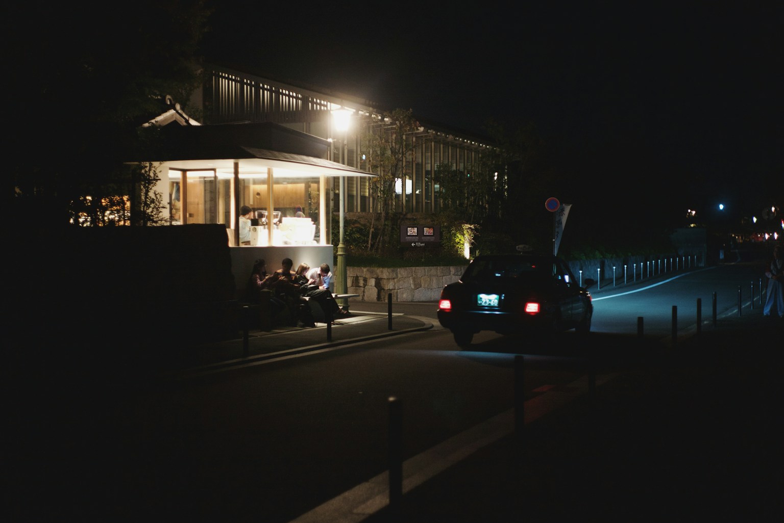 Ein hell erleuchtetes Restaurant bei Nacht mit einem geparkten Auto