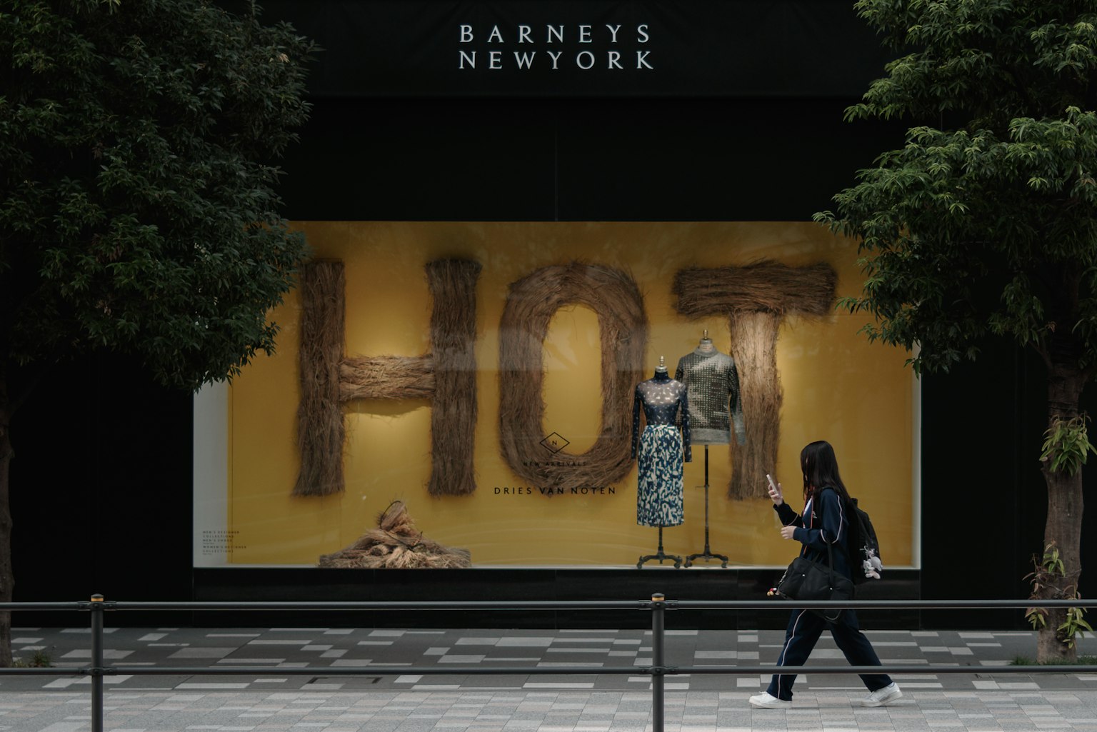 Vitrine de Barneys New York affichant le mot HOT et une personne passant