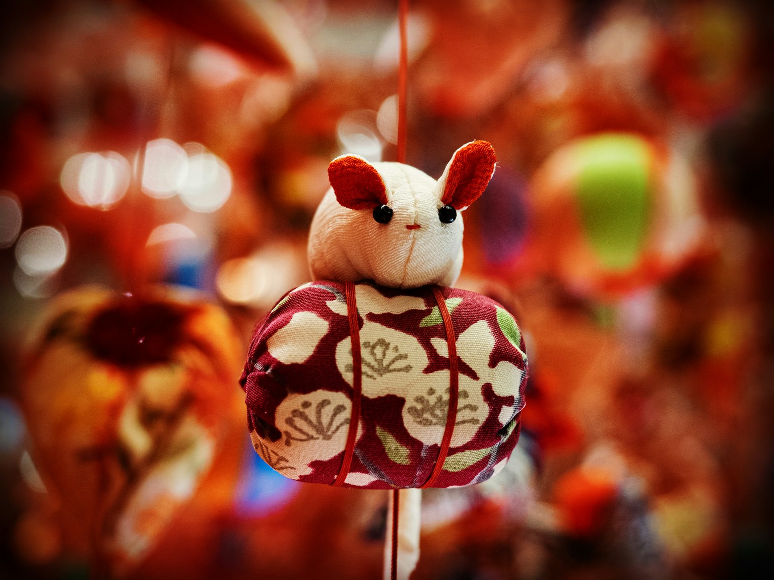 Una figura decorativa di coniglio con un kimono floreale appesa su uno sfondo colorato