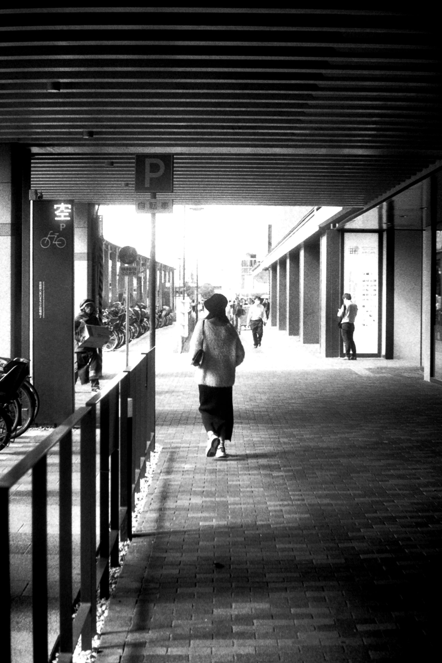 Una persona caminando en una escena de calle comercial en blanco y negro