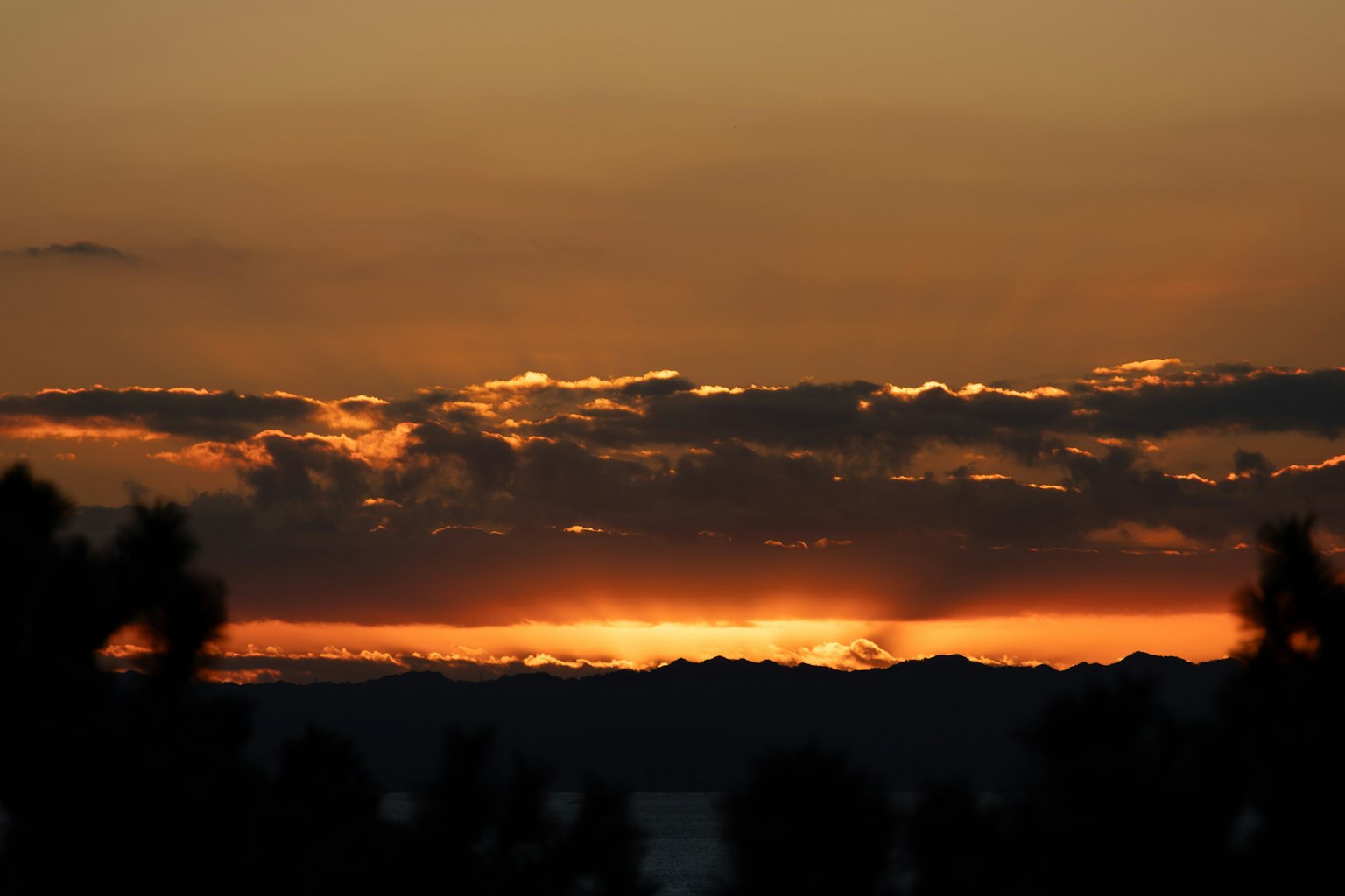 Bellissimo paesaggio al tramonto con contrasto arancione e nero silhouette di montagne
