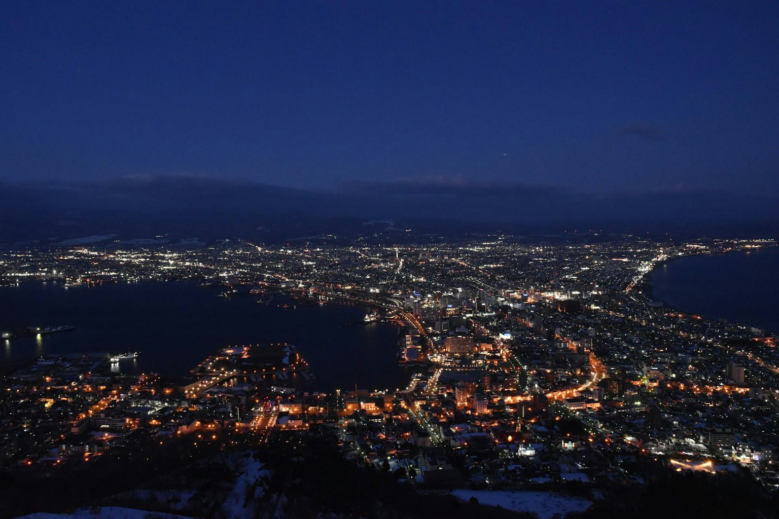 Vue panoramique nocturne de la ville de Hakodate montrant les lumières et l'océan