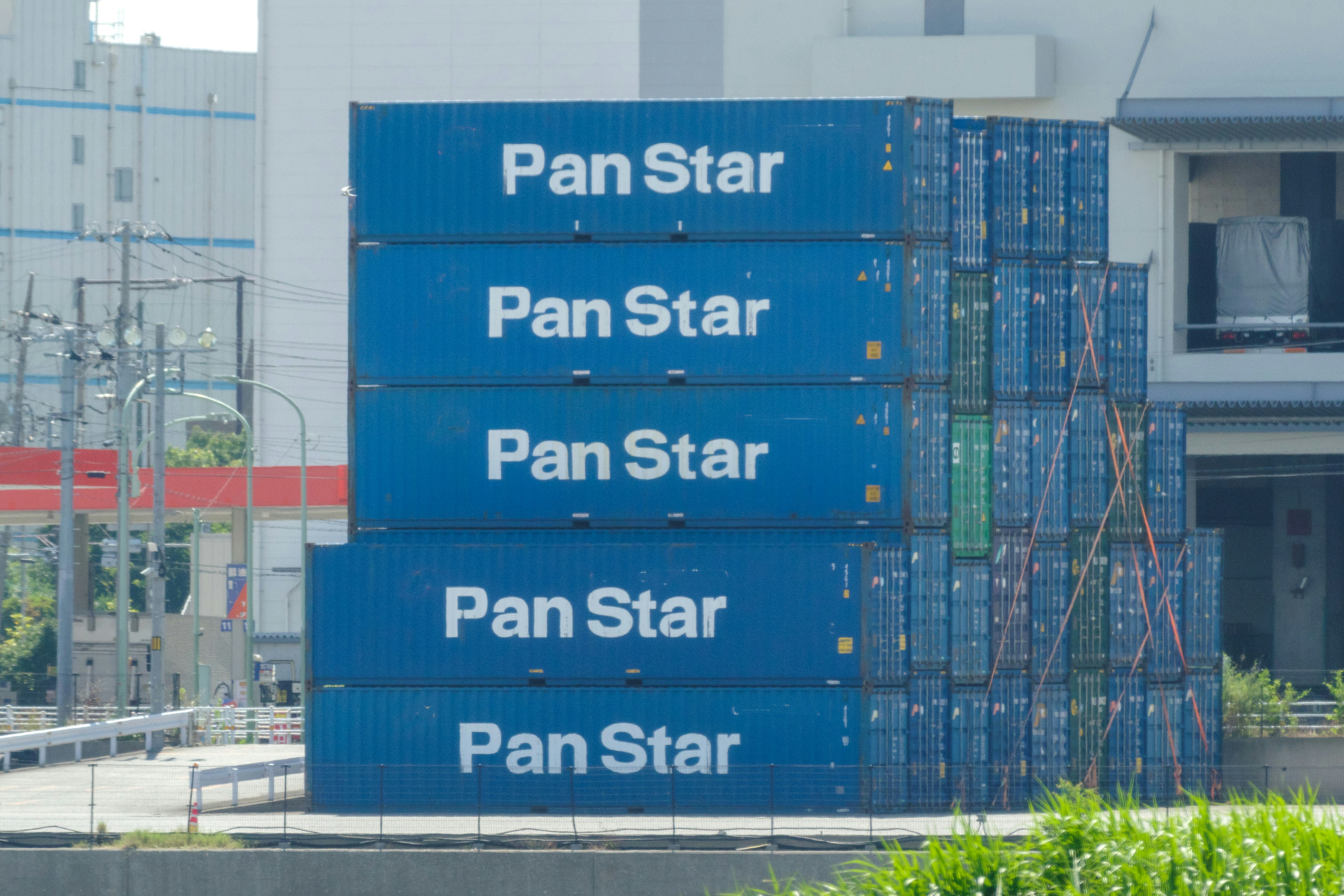 Pilones de contenedores azules con el logotipo “PanStar” en un sitio industrial