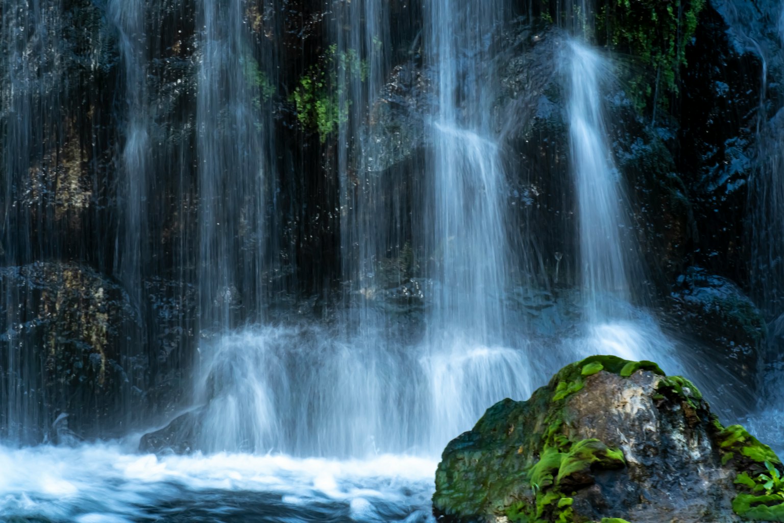 Hermosa cascada cayendo sobre rocas con musgo verde