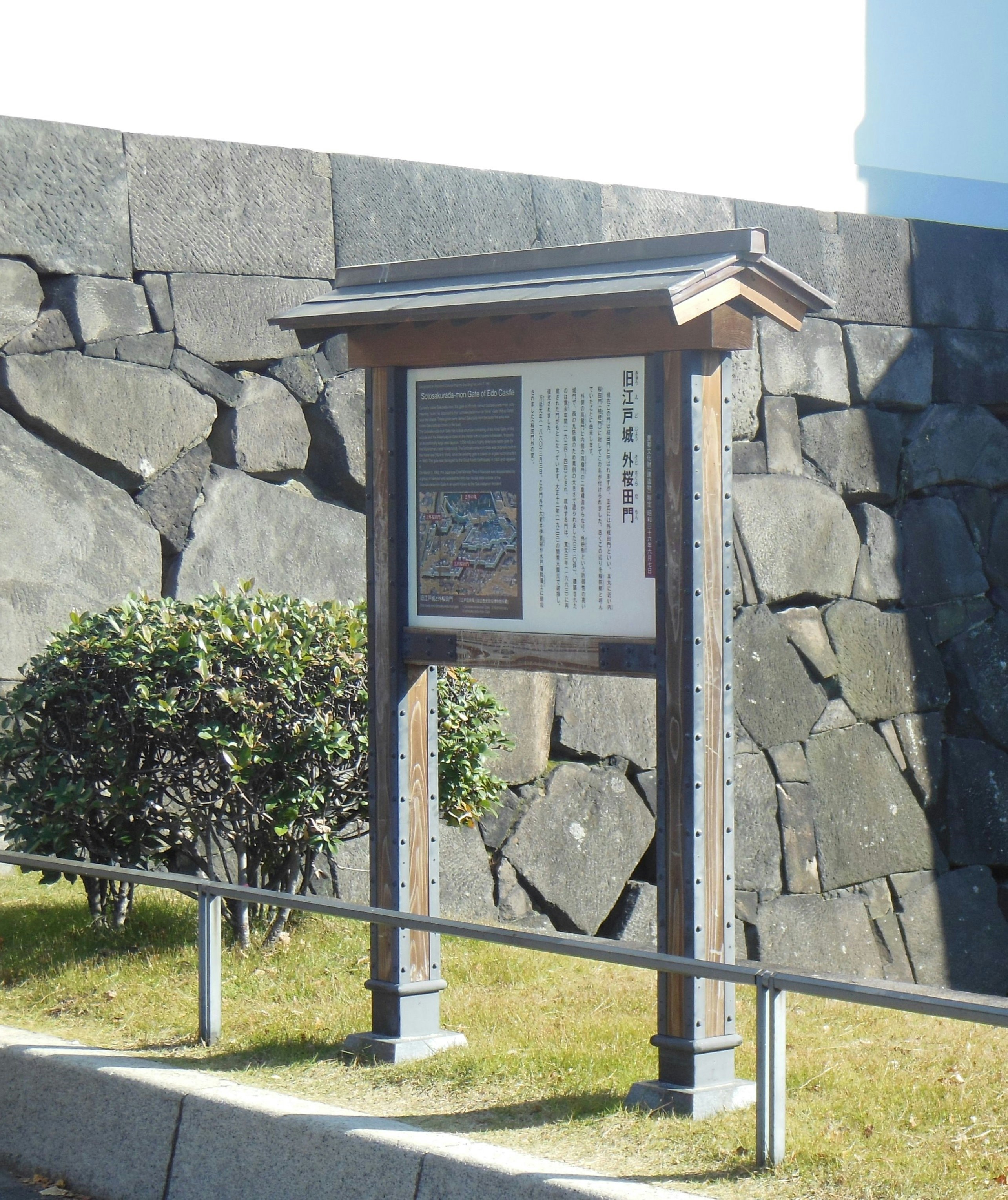 石垣の壁の前に設置された案内掲示板のある屋外展示スペース