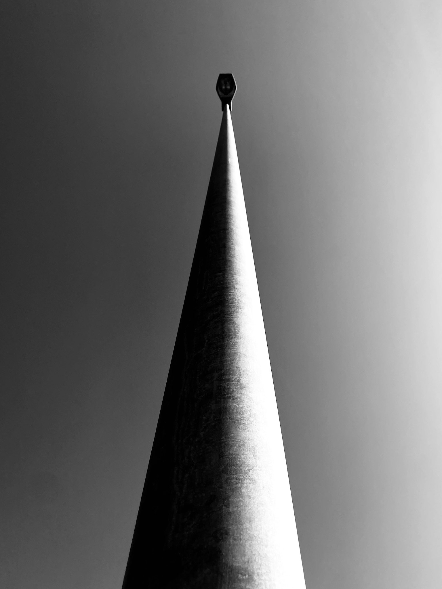 尖った形状の塔の上部が見えるモノクロ写真