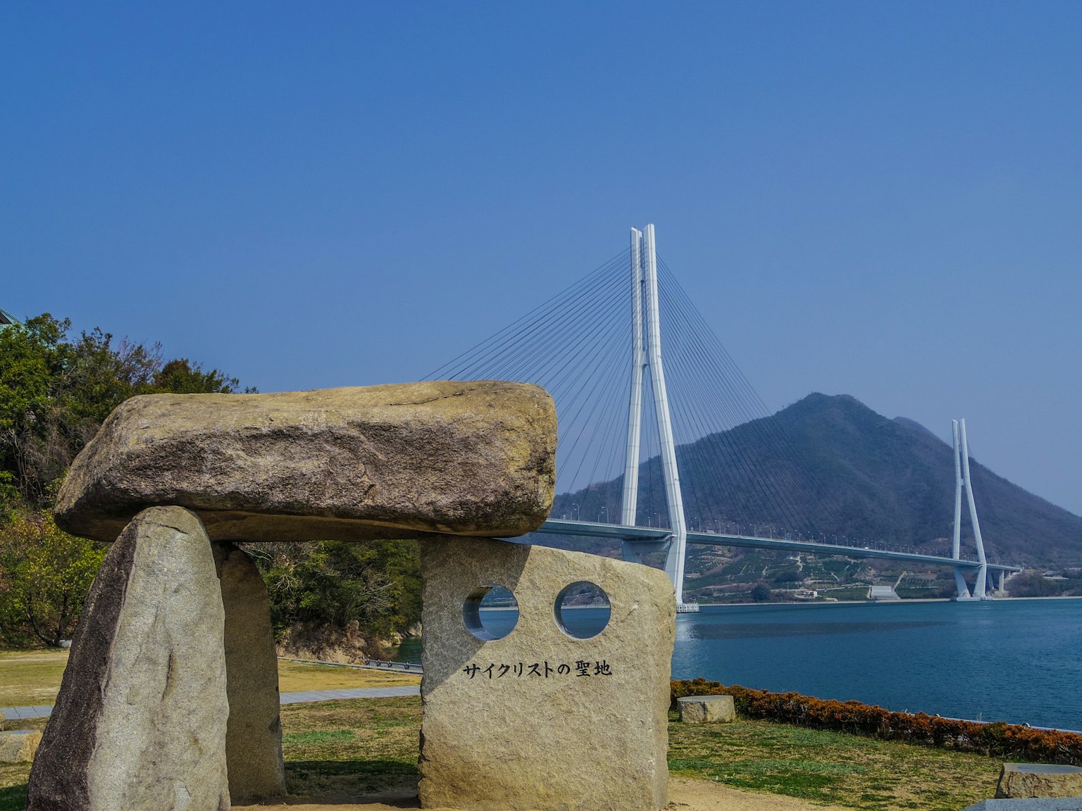 Steinskulptur und Denkmal mit einer Brücke und einem Berg im Hintergrund