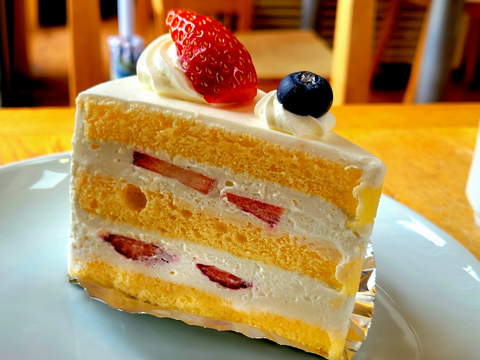 Tranche de gâteau éponge jaune garnie de crème et de fraises
