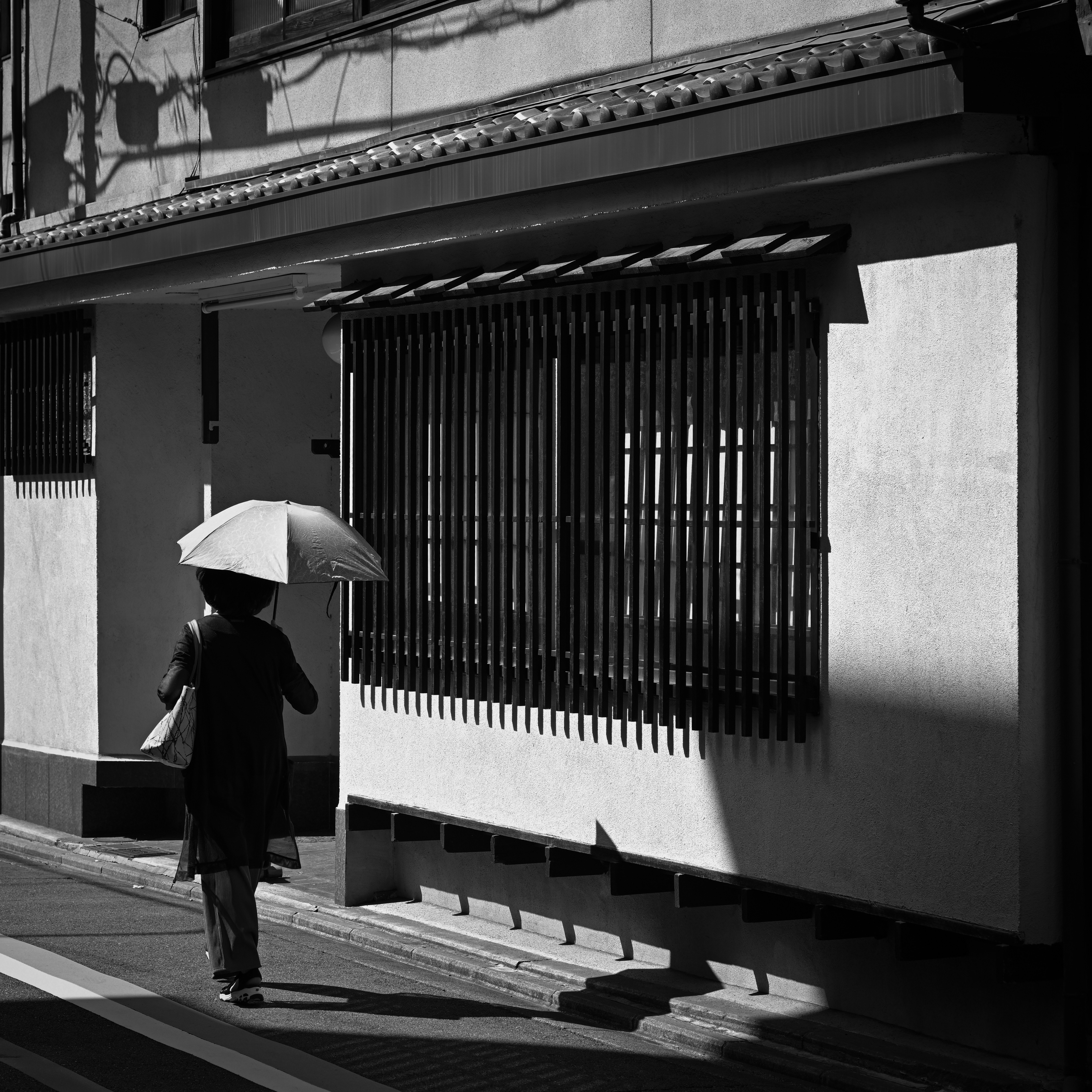 京都の路地で日傘をさすひとりの後ろ姿