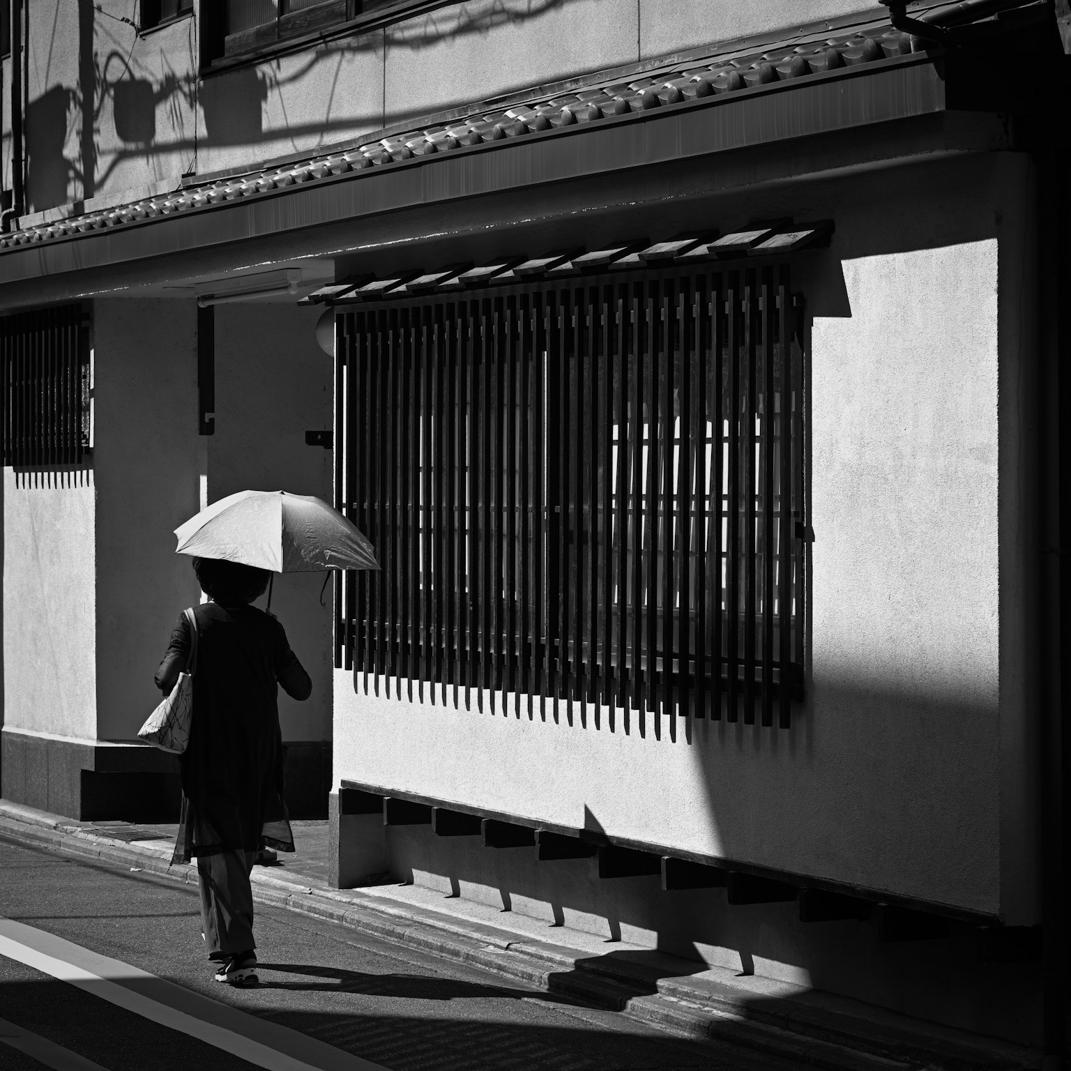 在黑白城市環境中走著的女人，手持雨傘