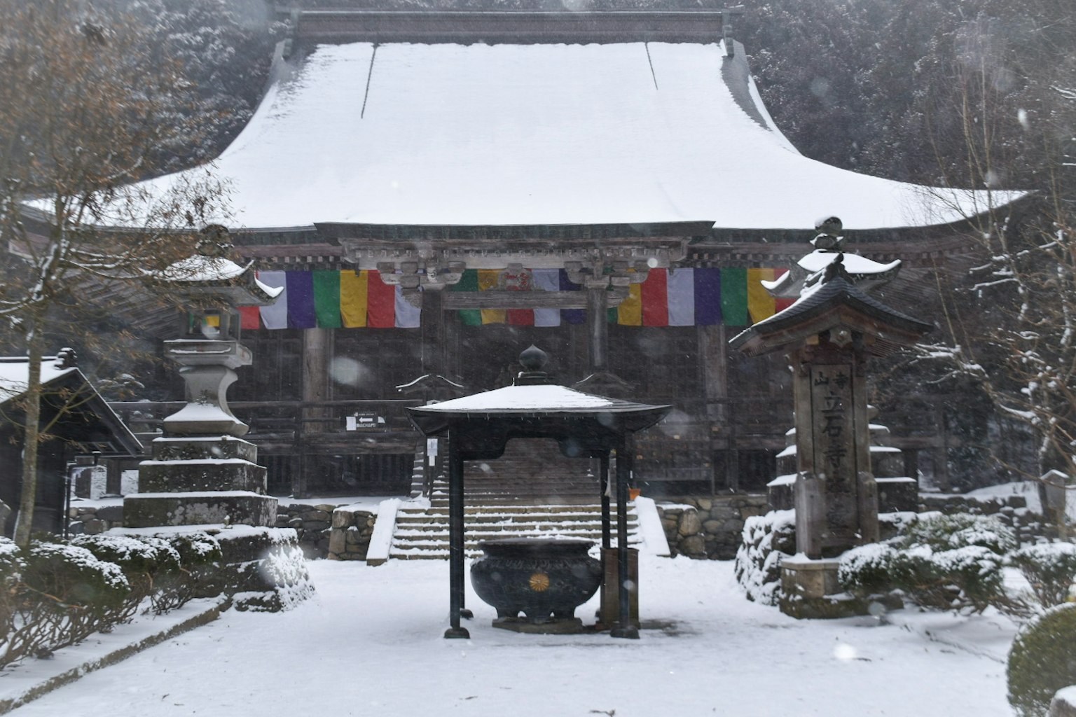 Temple recouvert de neige avec des drapeaux de prière colorés au premier plan