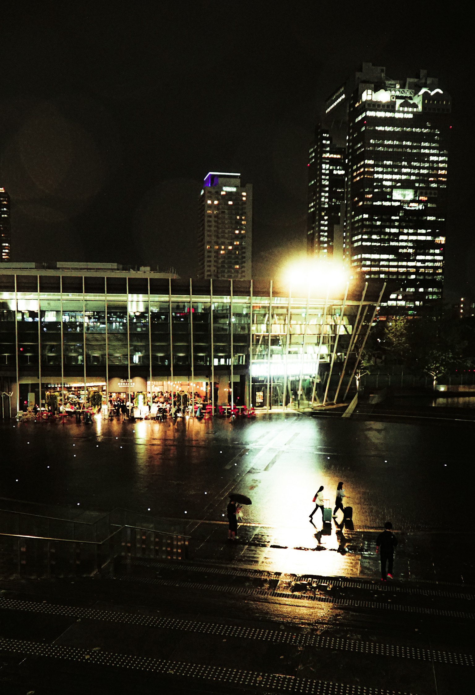 Bâtiment moderne et gratte-ciels illuminés la nuit dans un paysage urbain