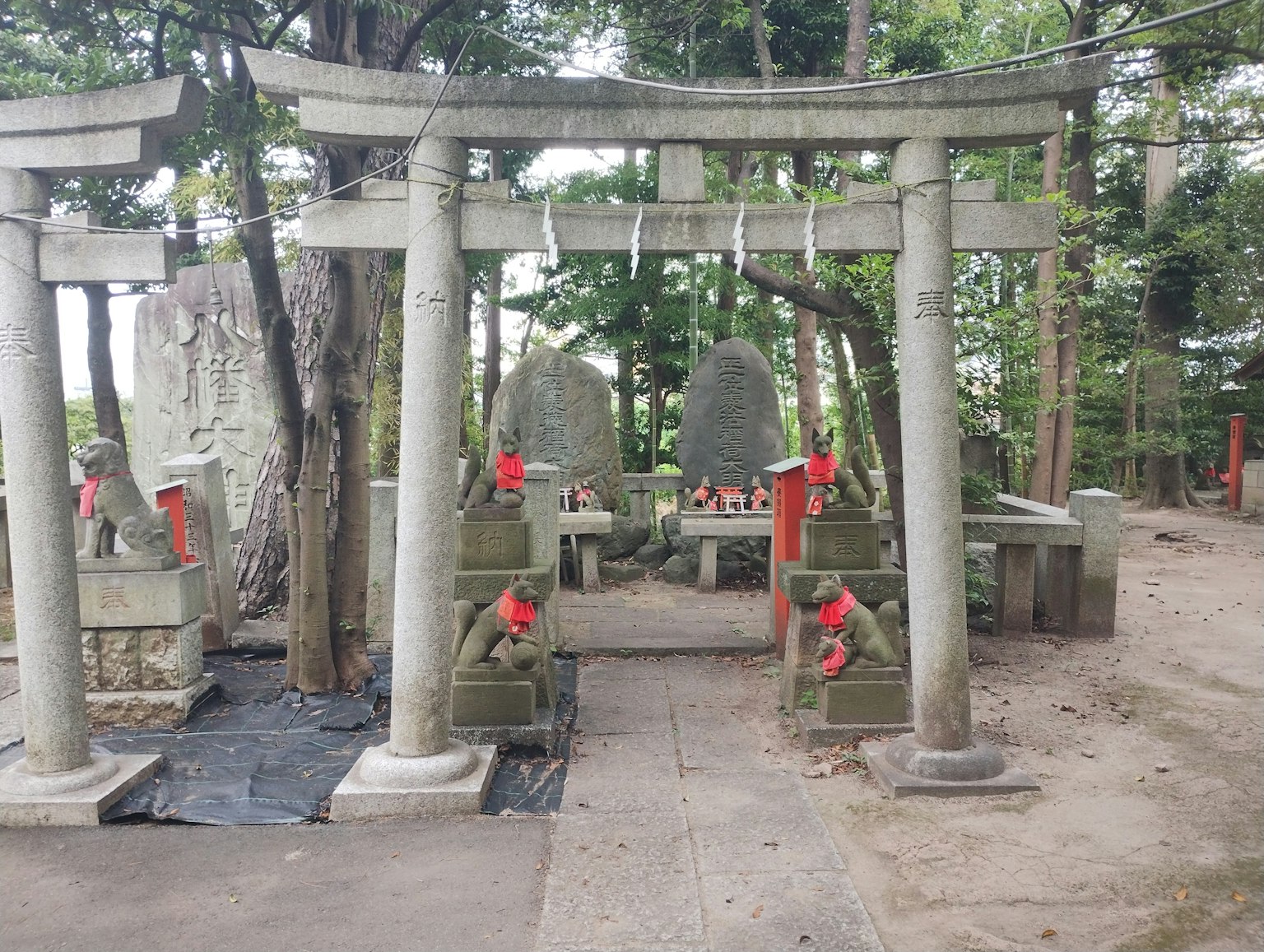 Escena forestal con un torii y monumentos de piedra decorados con rojo