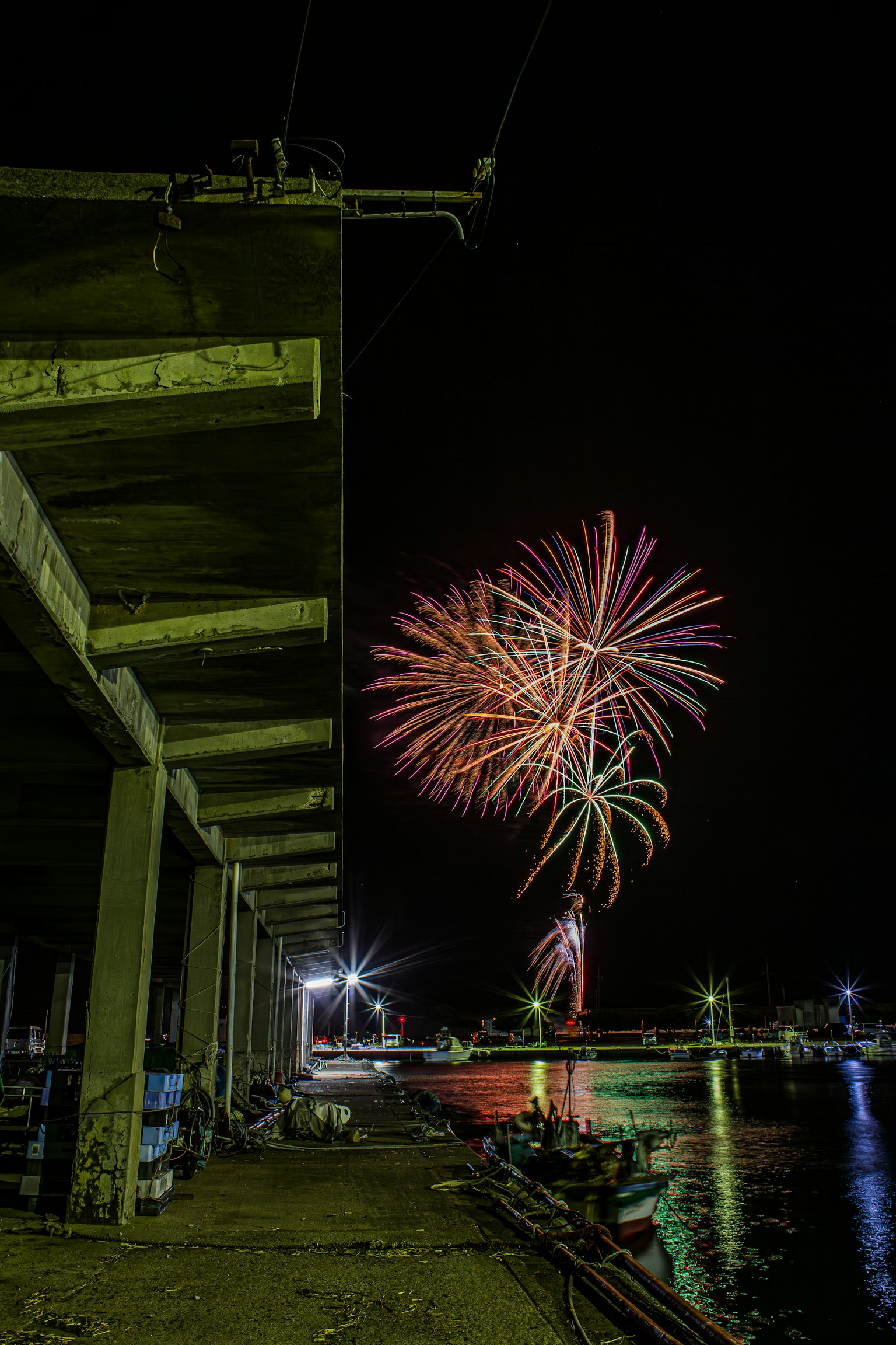 Fuegos artificiales iluminando el cielo nocturno sobre un puerto