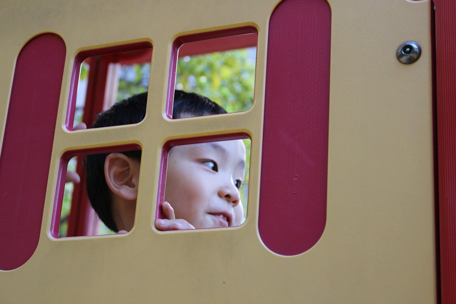 Niño mirando a través de una ventana de una estructura de juego
