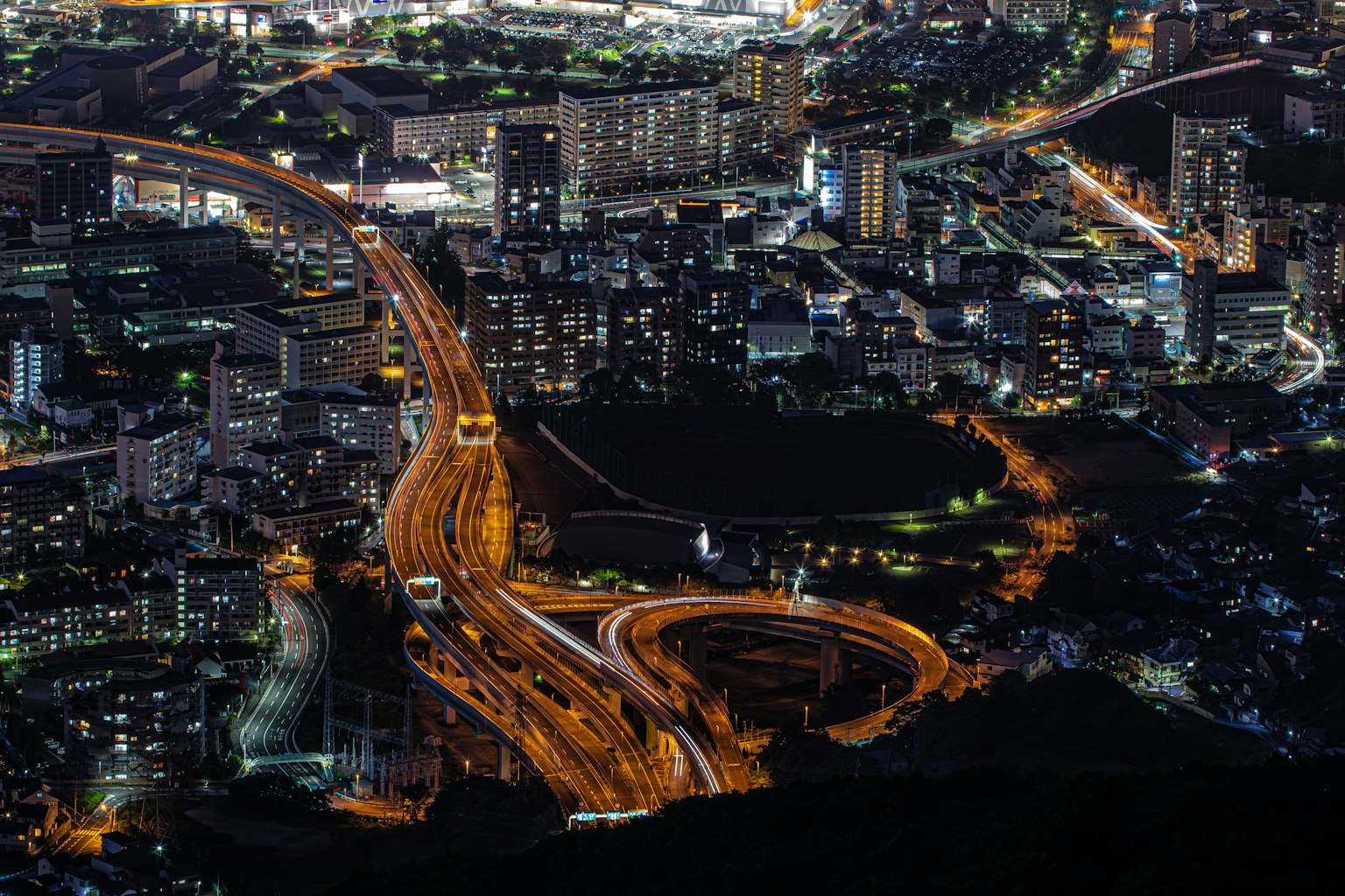 Night cityscape featuring illuminated highways and buildings