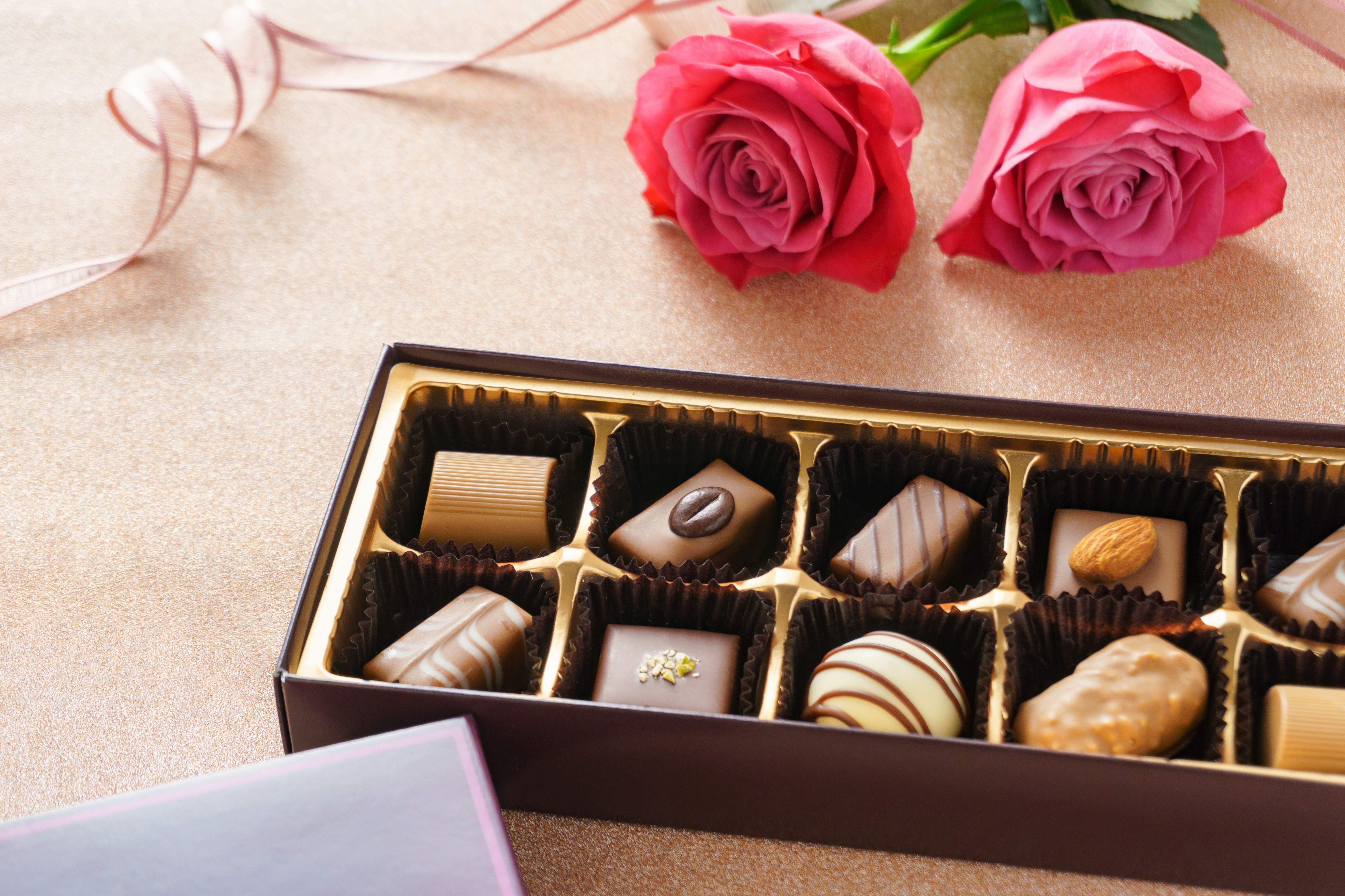 Geschenkschachtel mit Pralinen und rosafarbenen Rosen