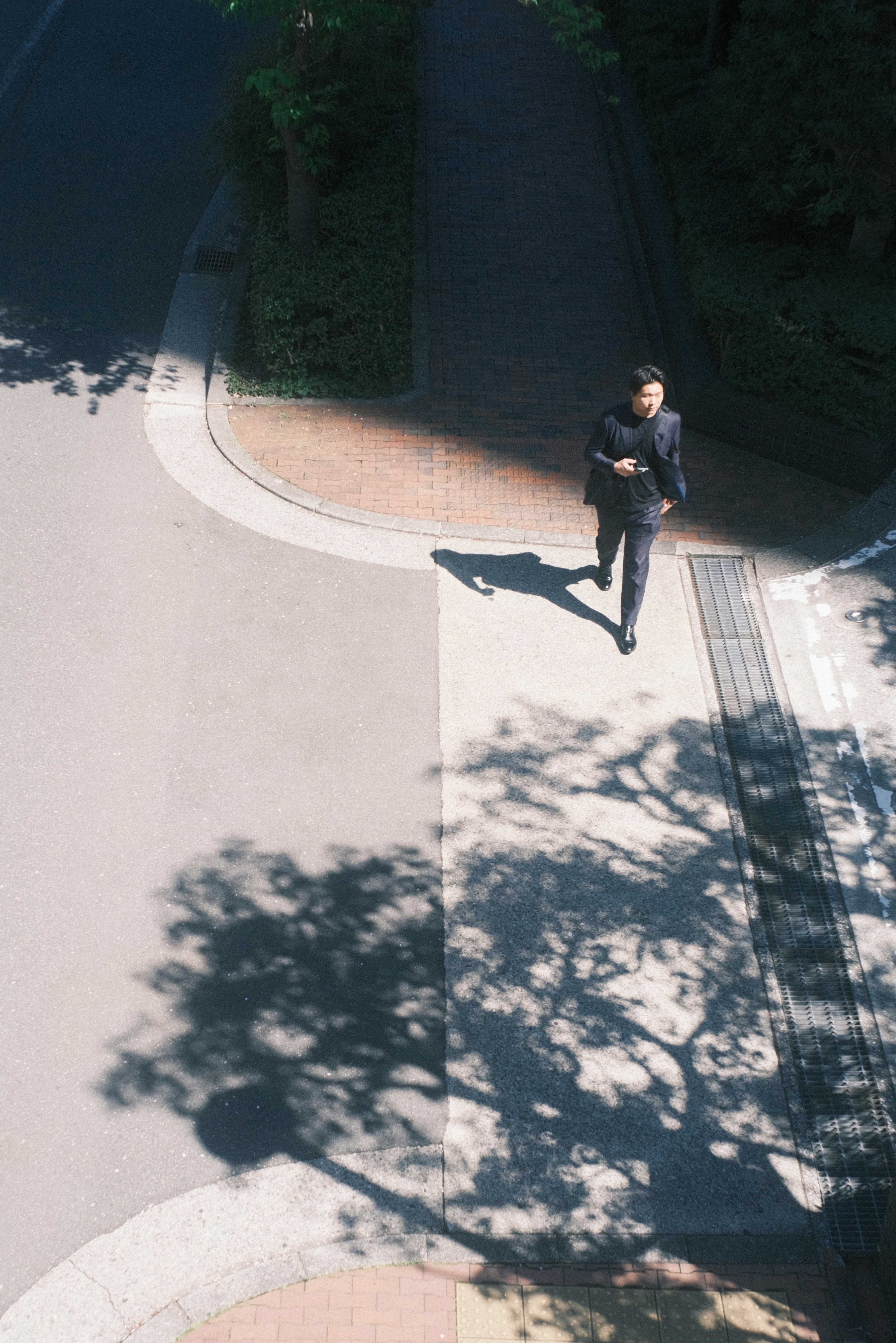 木陰の落ちる路地で歩く人物