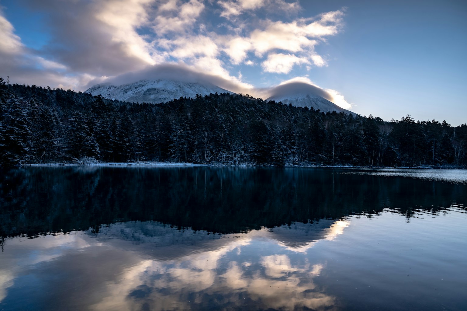 Winter landscape featuring snow-covered mountains and serene lake reflections