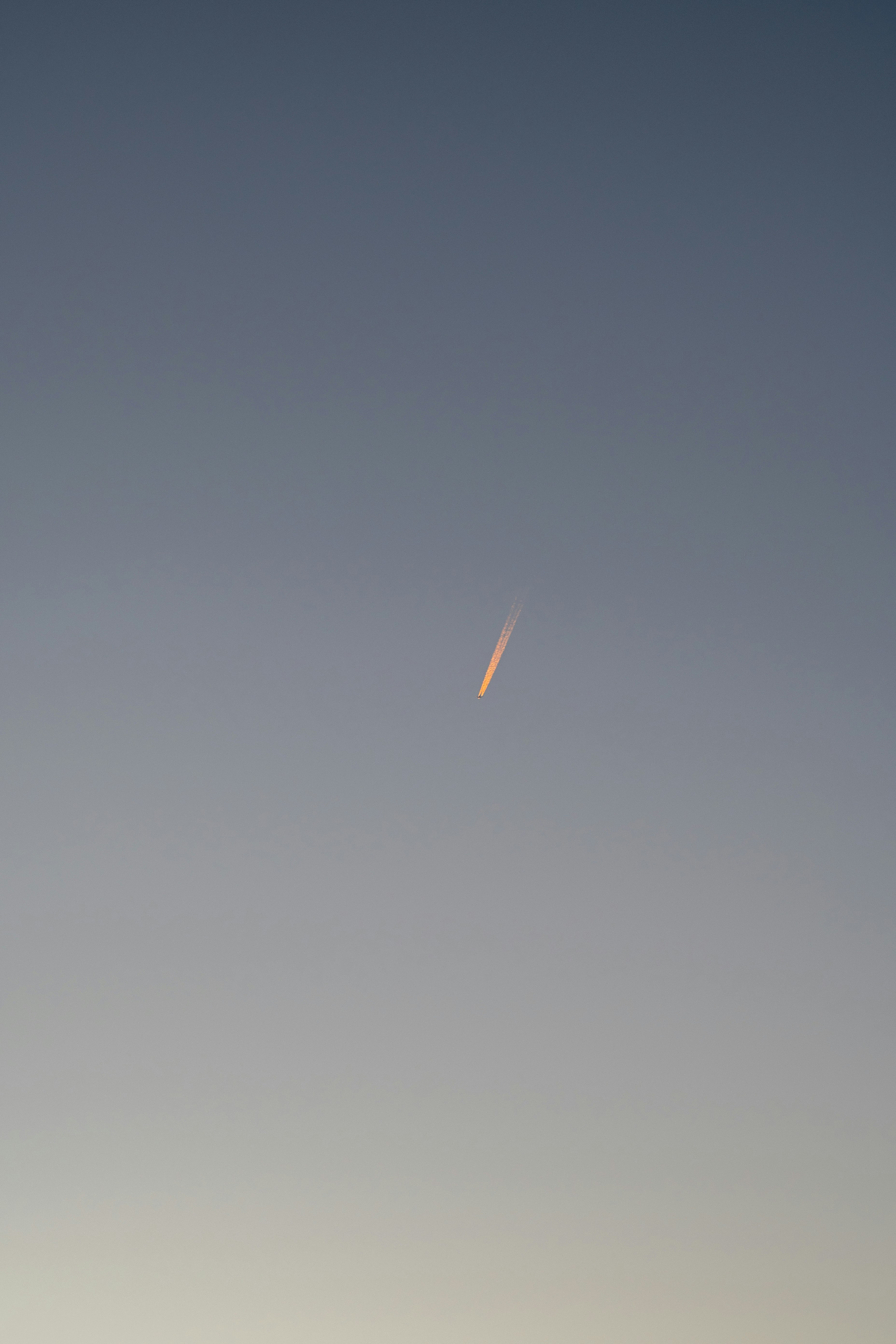 青空に細い流れ星のような光跡