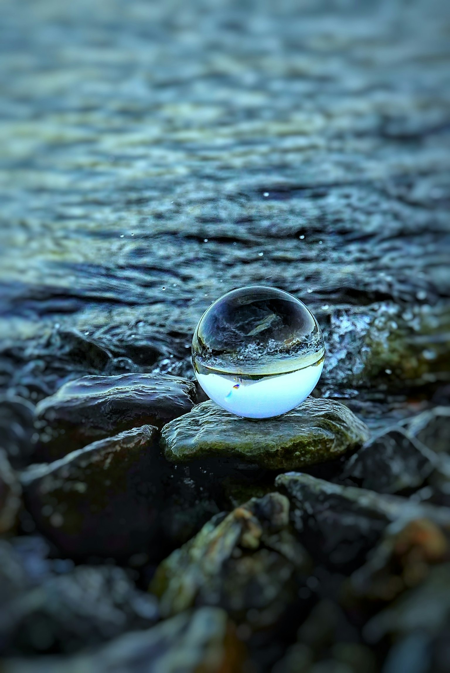 Crystal ball resting on rocks by water surface