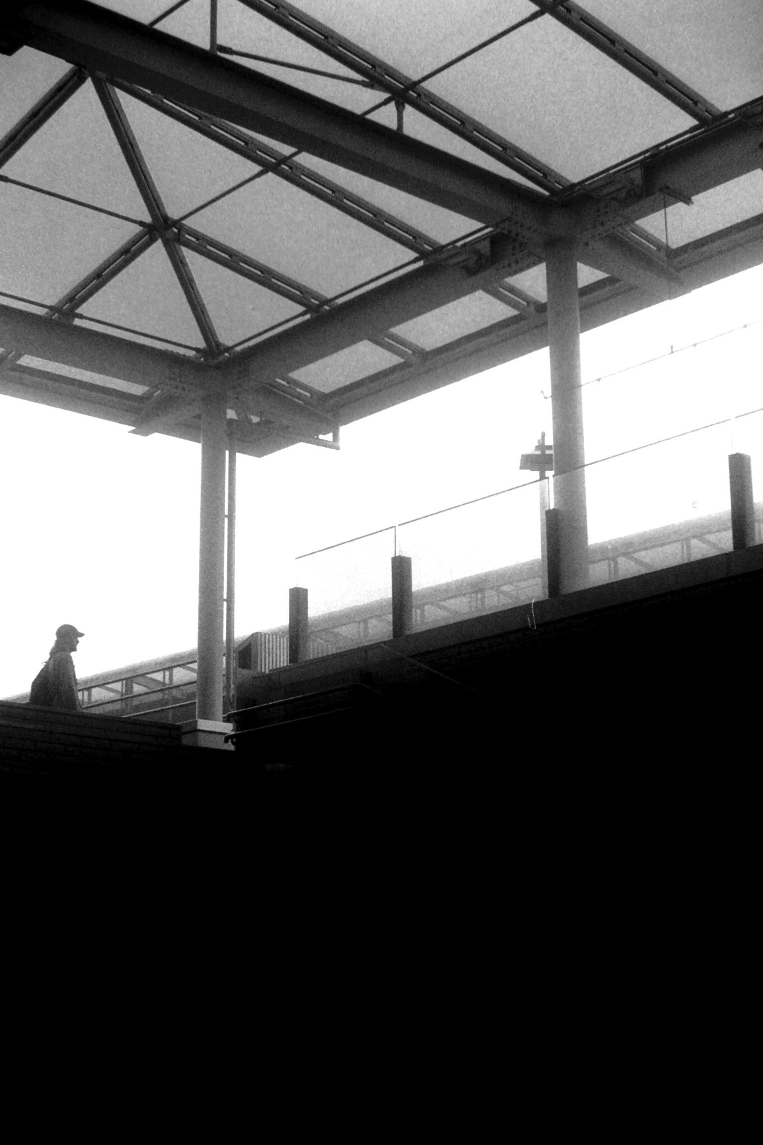 Silueta de una persona de pie en una plataforma de tren con un techo transparente