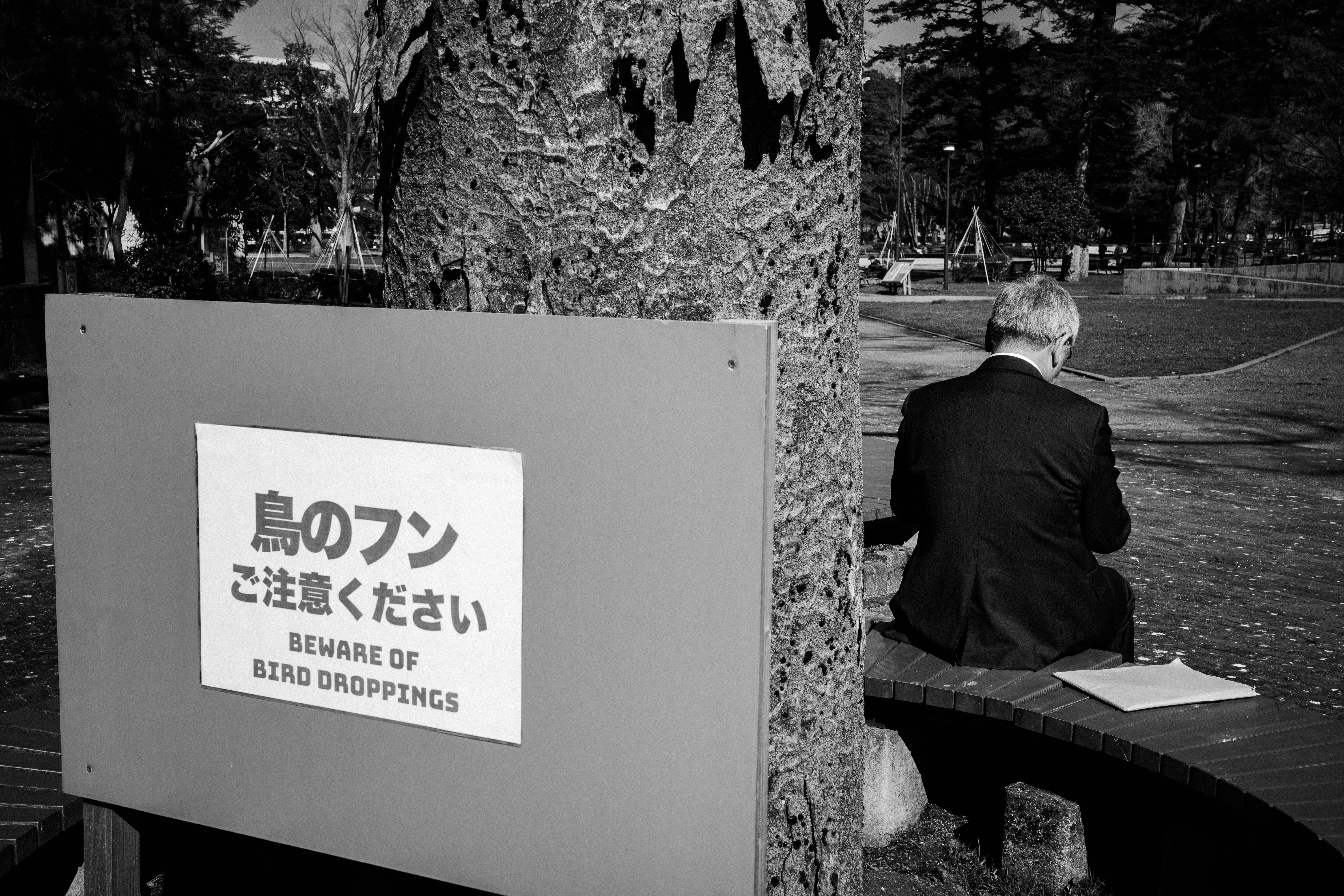 公園長椅旁坐著的人和警示牌場景