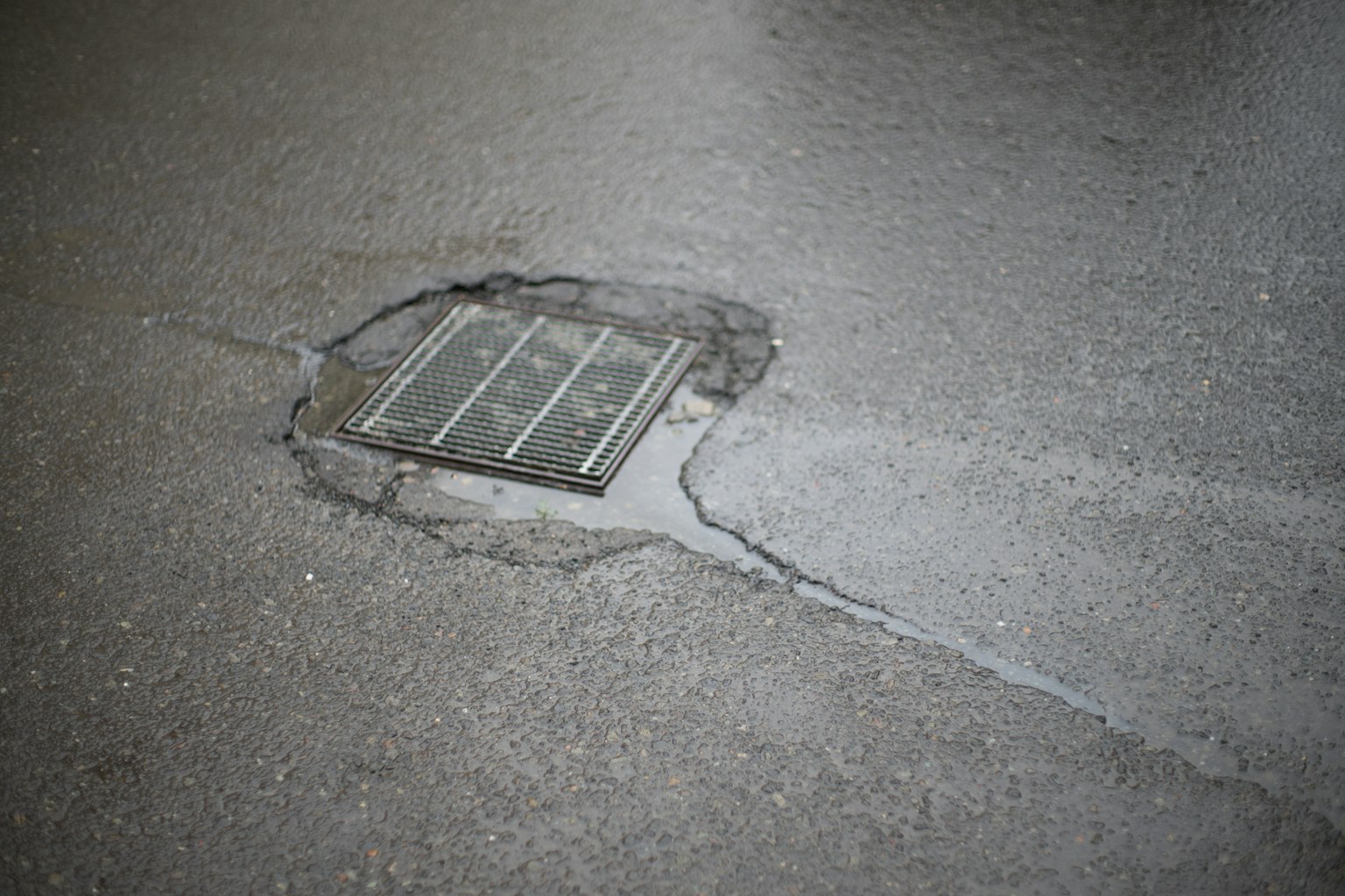 A street drain with a puddle of water around it