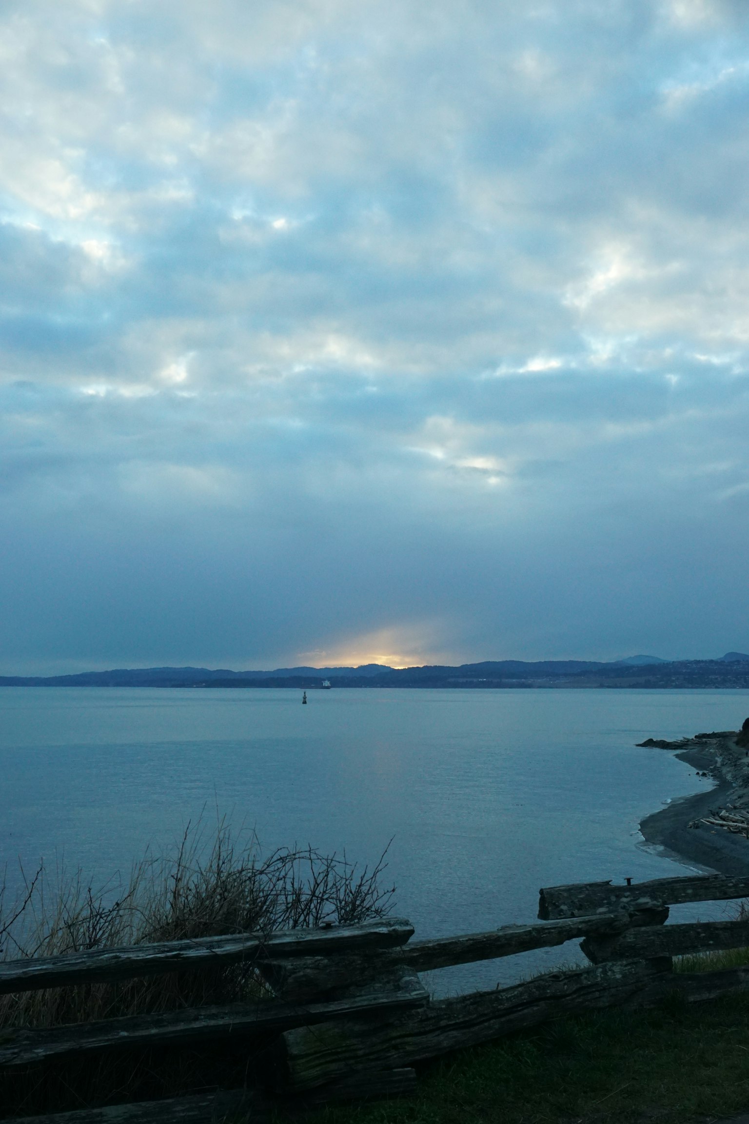 ทิวทัศน์ทะเลสงบและท้องฟ้าหมอกควันพร้อมแสงพระอาทิตย์ตกสะท้อนบนผิวน้ำ