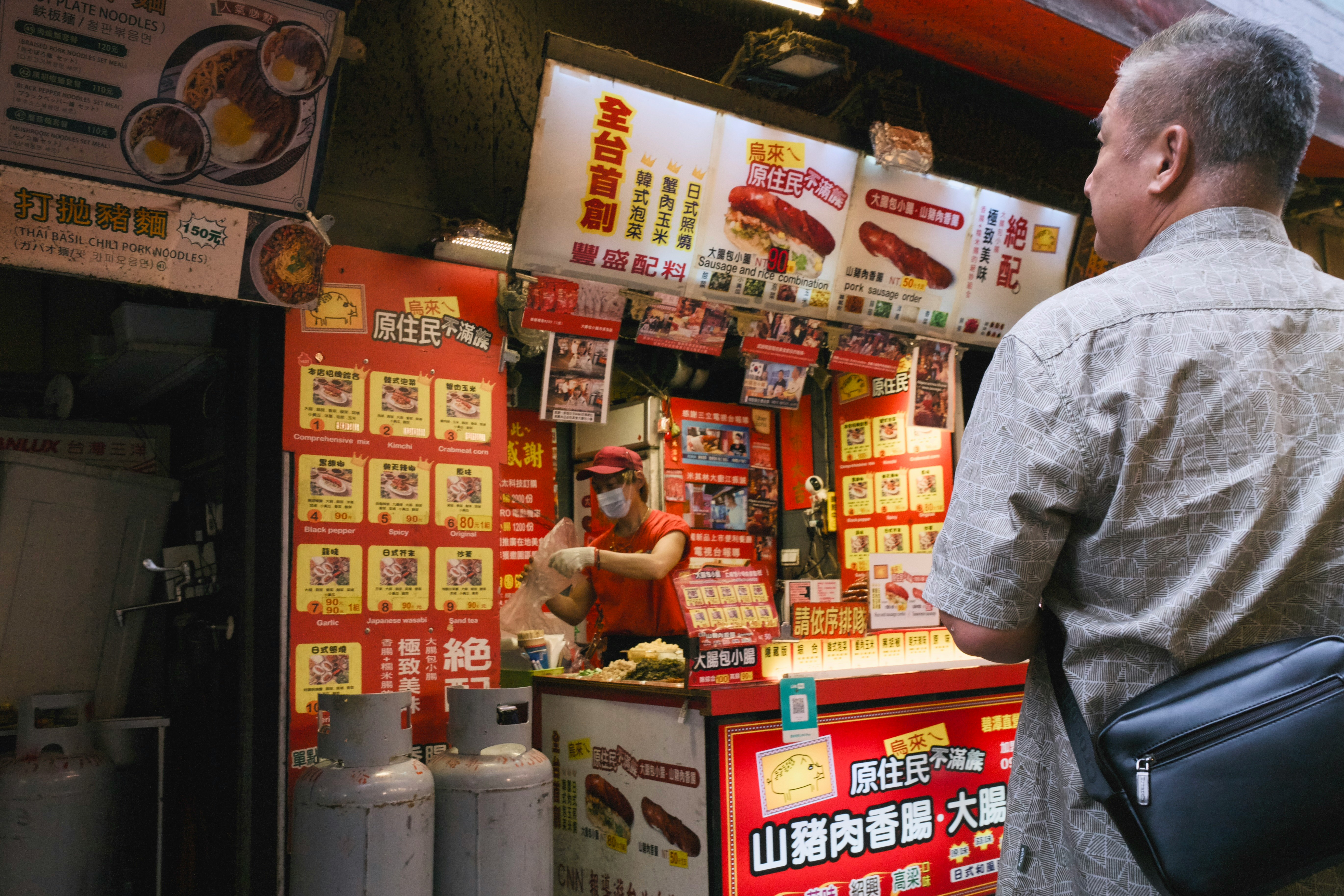 屋台のメニュー看板と客の後ろ姿がある路地の飲食店