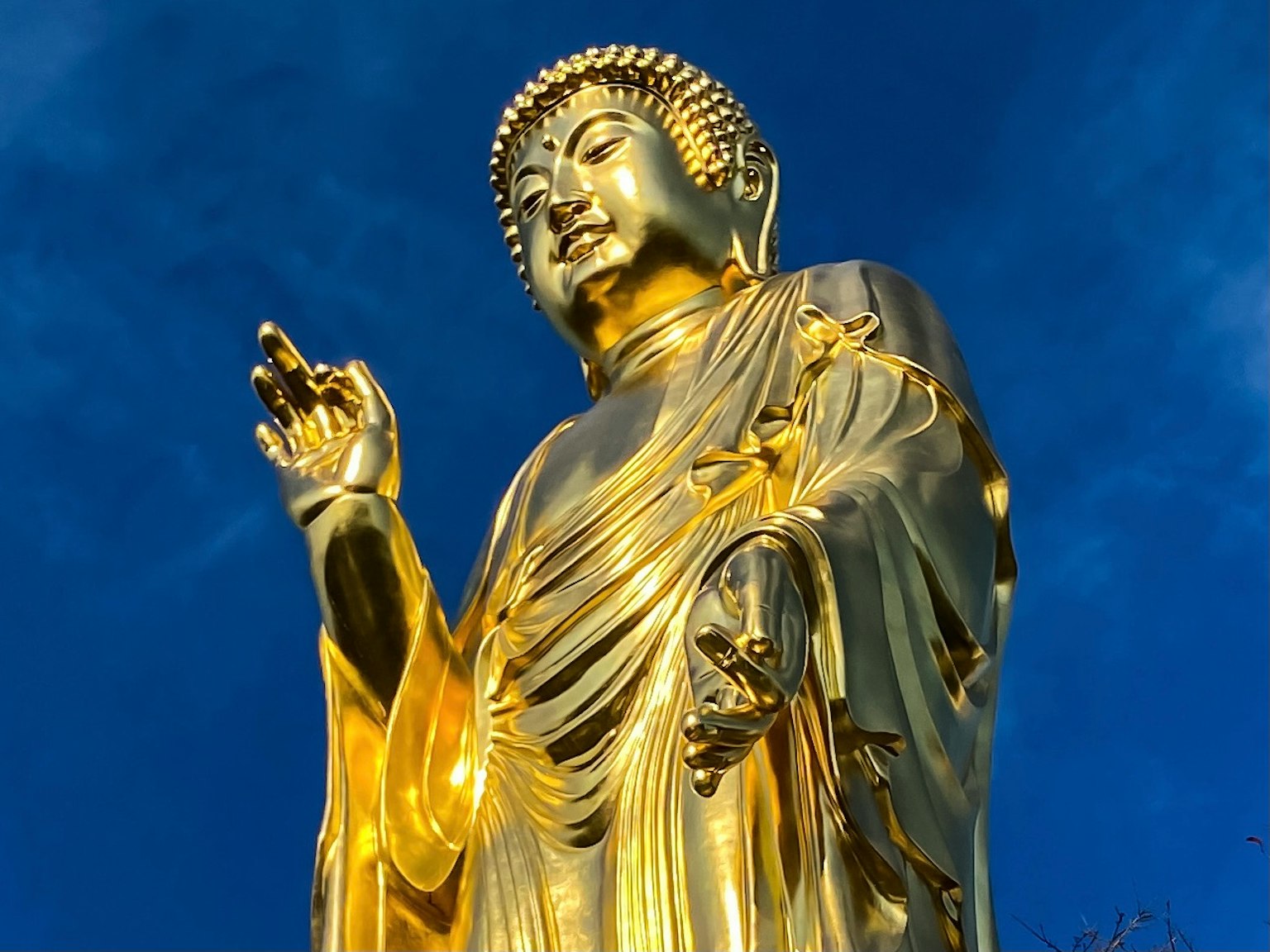 Statua di Buddha dorata si erge contro un cielo blu
