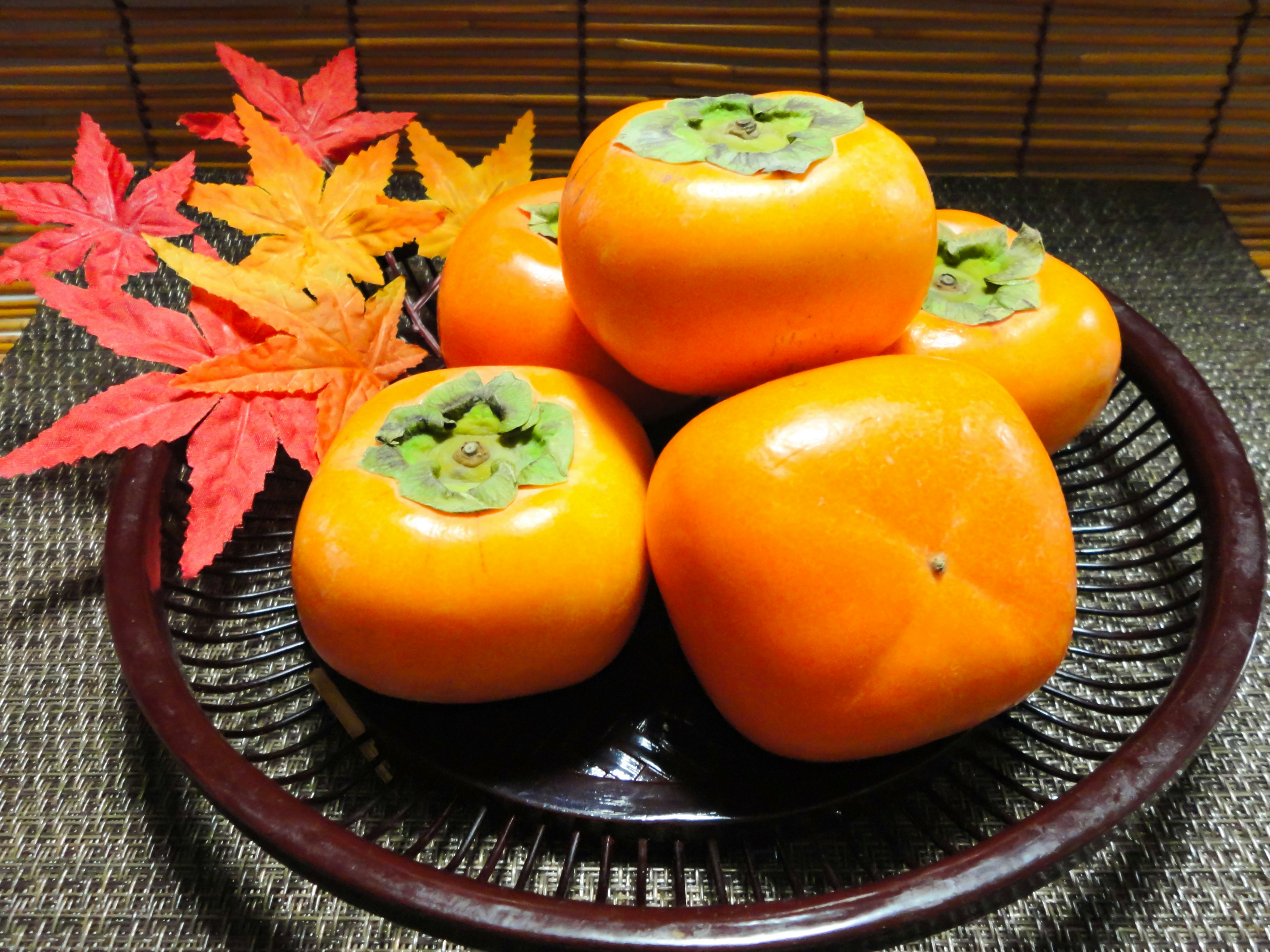 器に盛られた柿と紅葉のような葉