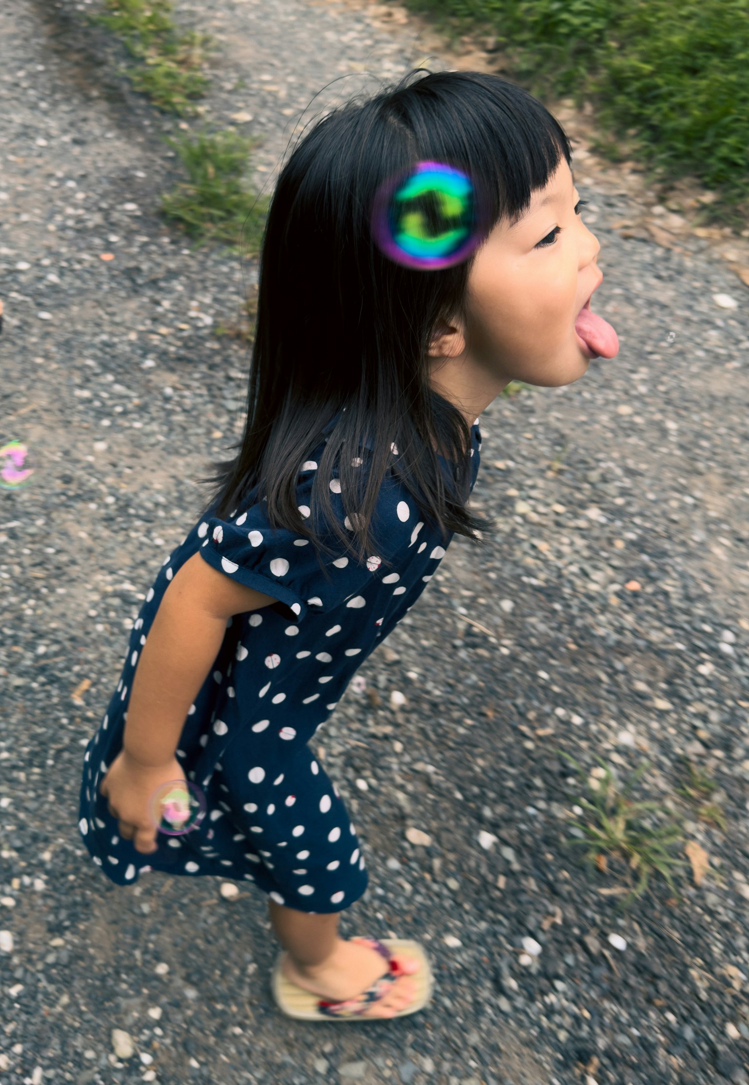 孩子站在小路上穿著波點裙子伸出舌頭