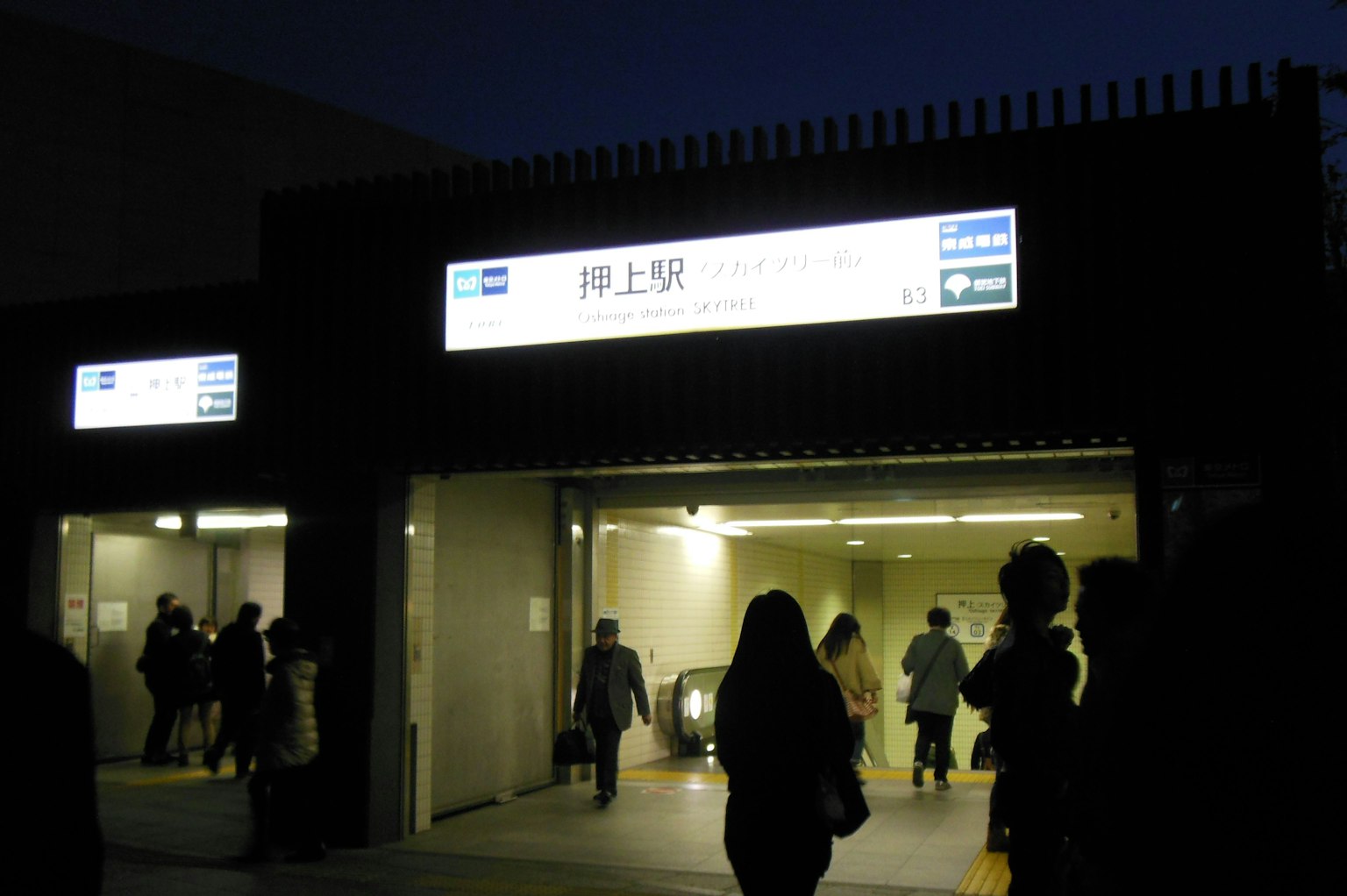 Persone che passano davanti all'ingresso di una stazione ferroviaria di notte