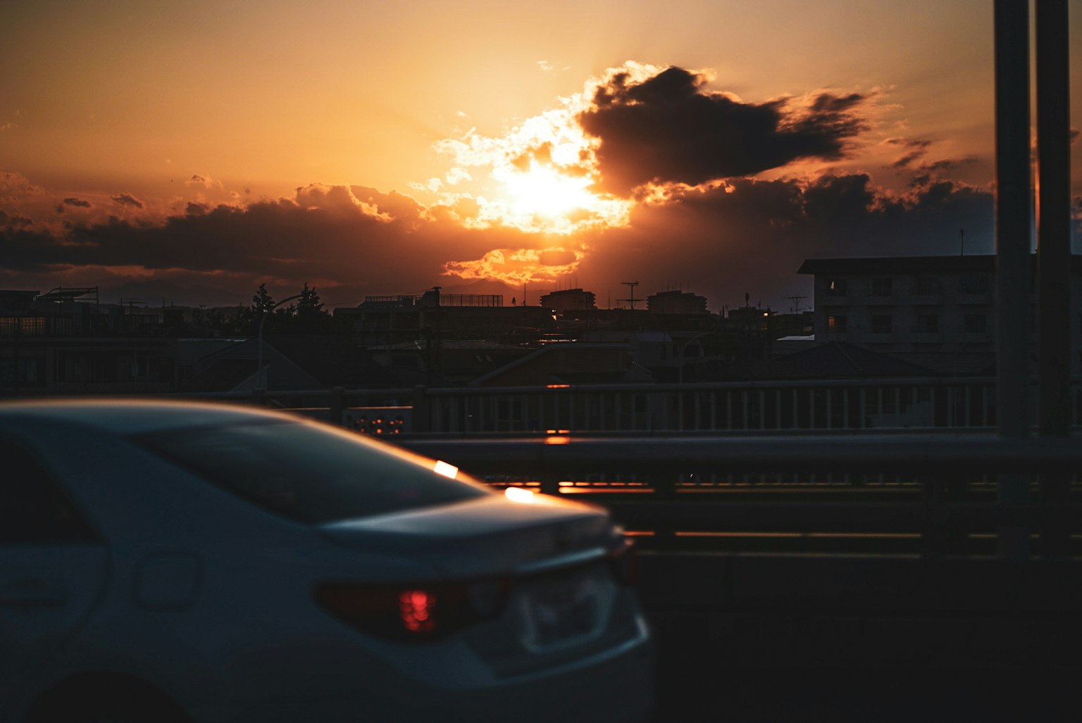 Un'auto che attraversa un ponte al tramonto con nuvole