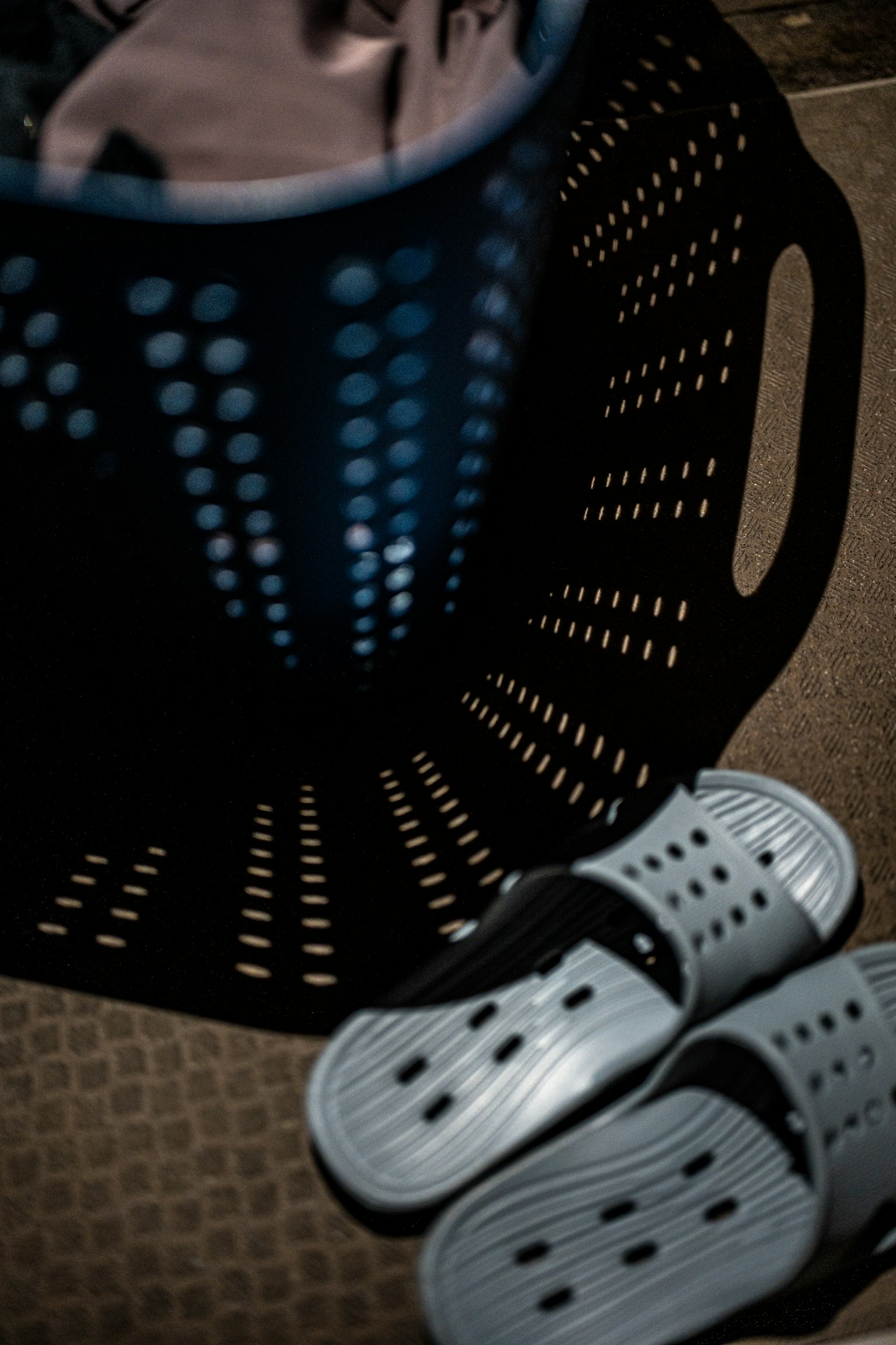 青い洗濯かごとグレーのスリッパが床に置かれている