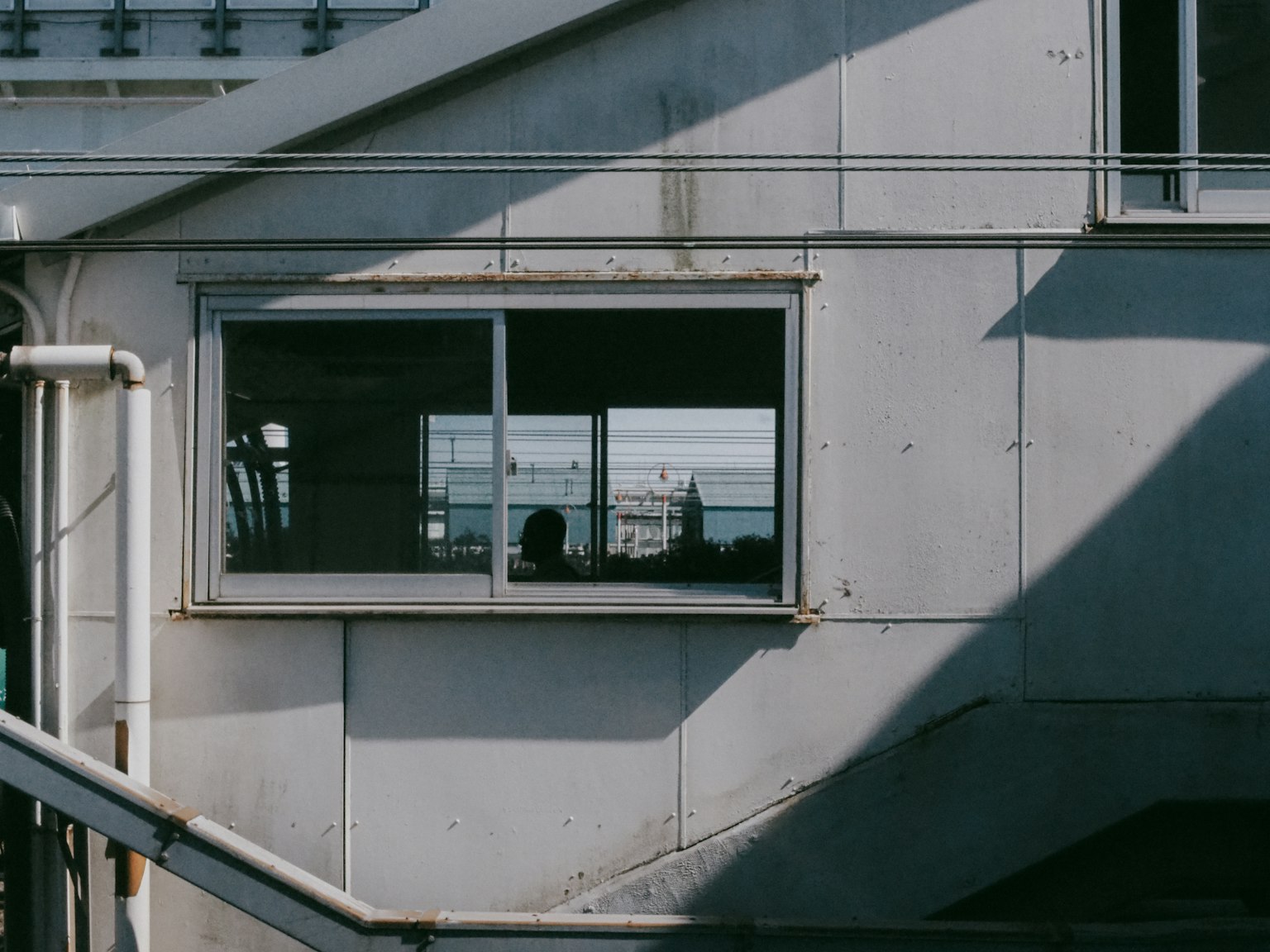 Côté d'un bâtiment industriel avec une fenêtre montrant une personne regardant à l'extérieur