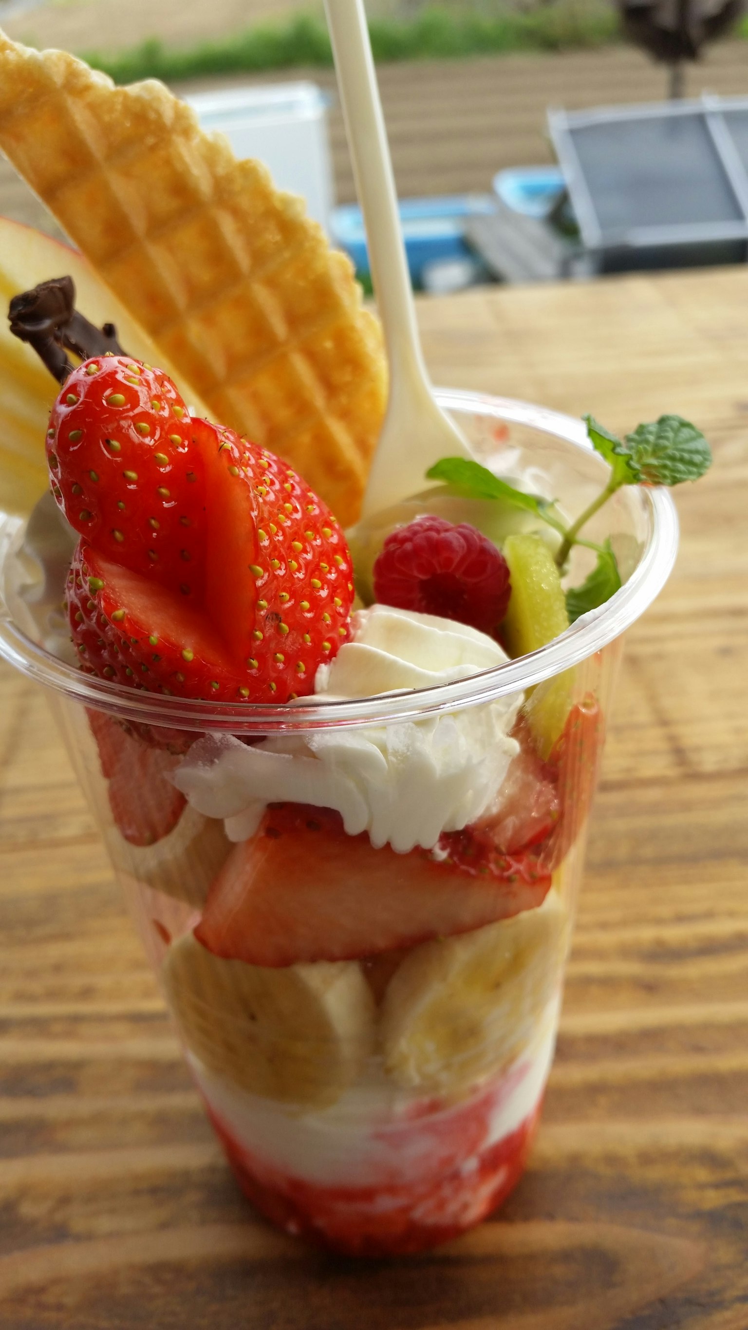 Dessert in einem Becher mit Früchten und Sahne, garniert mit Erdbeeren und Himbeeren