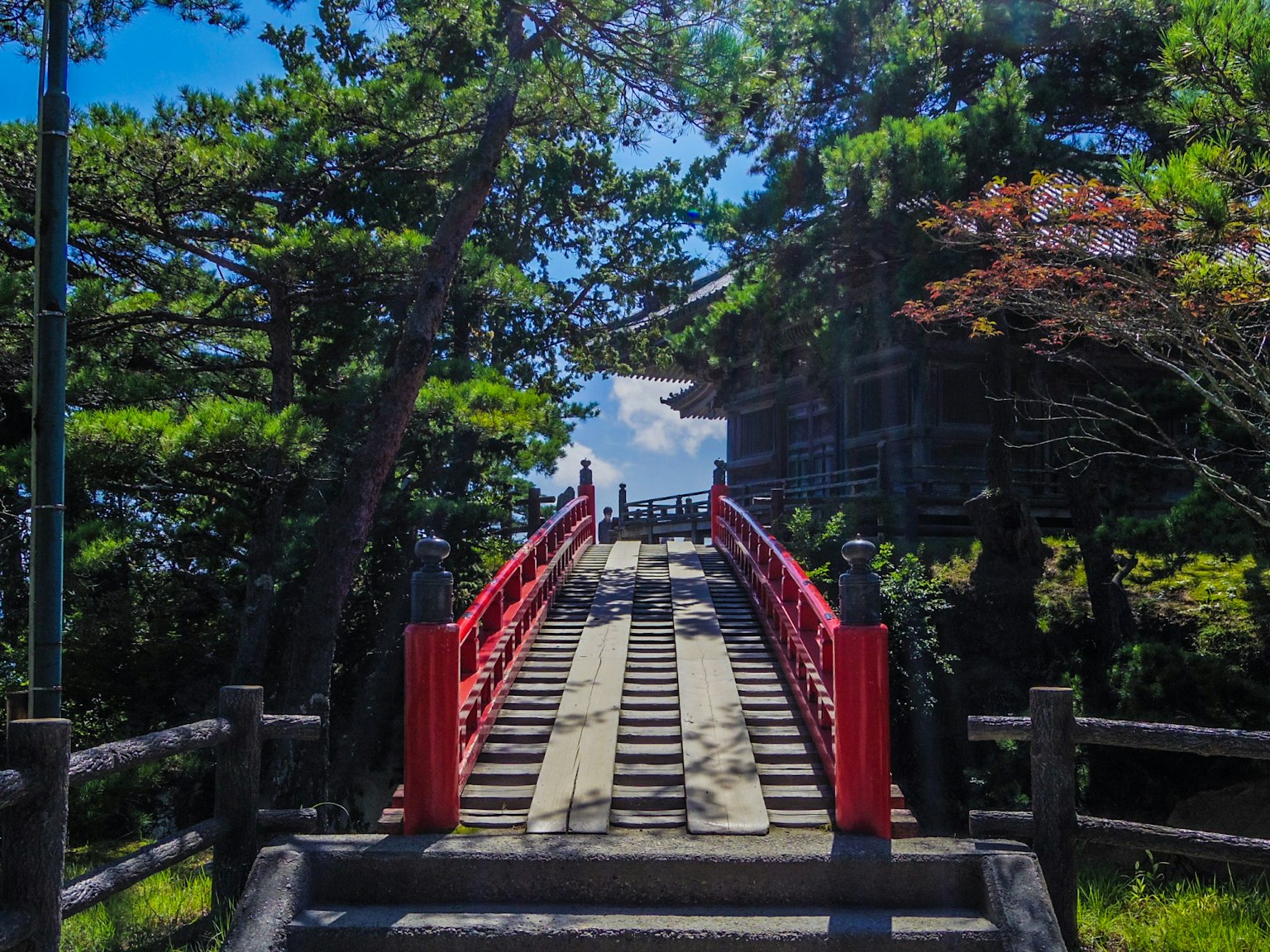 Scène pittoresque avec un pont rouge et une végétation luxuriante