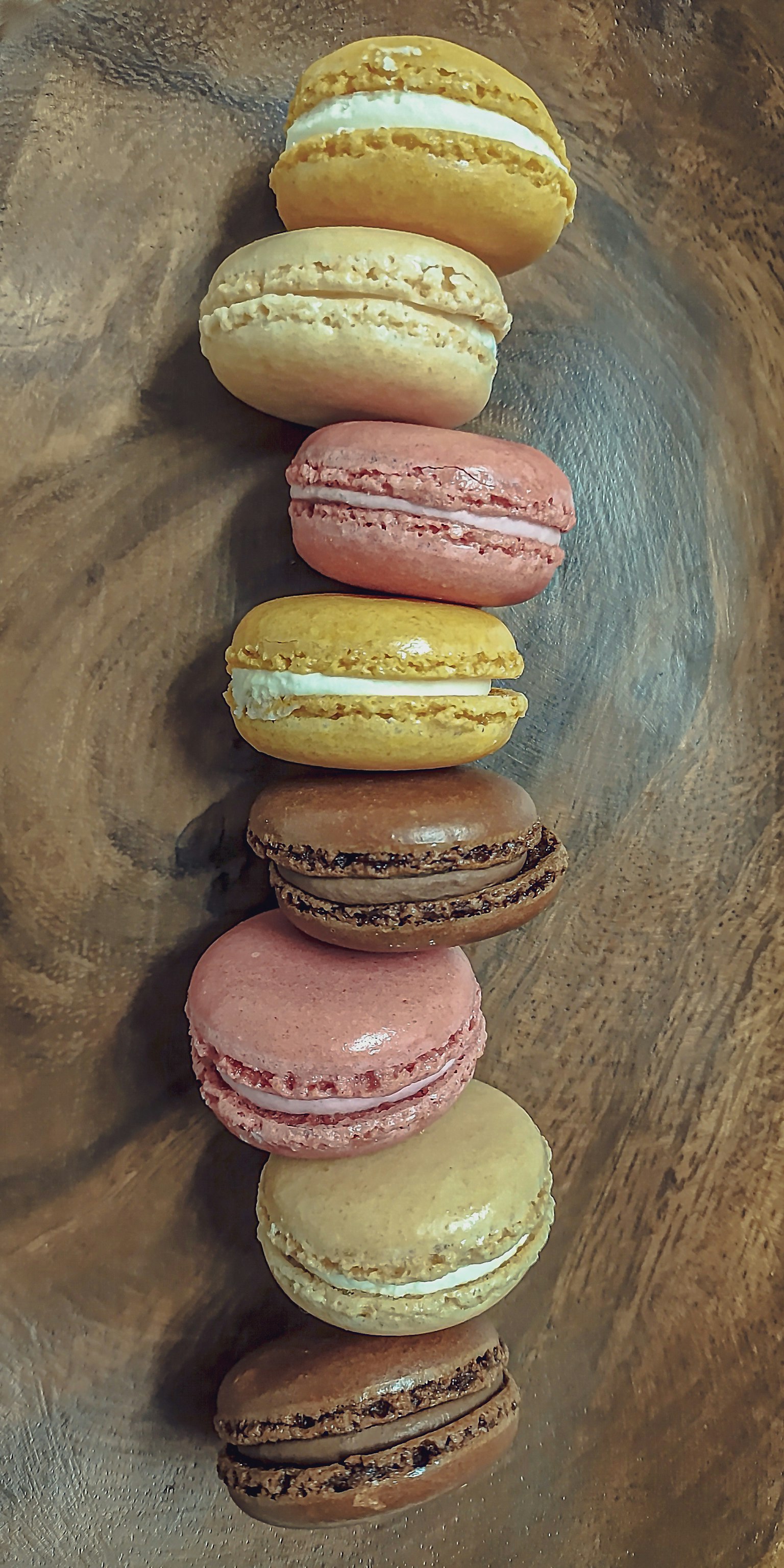 Macaron nhiều màu sắc được sắp xếp trên đĩa gỗ