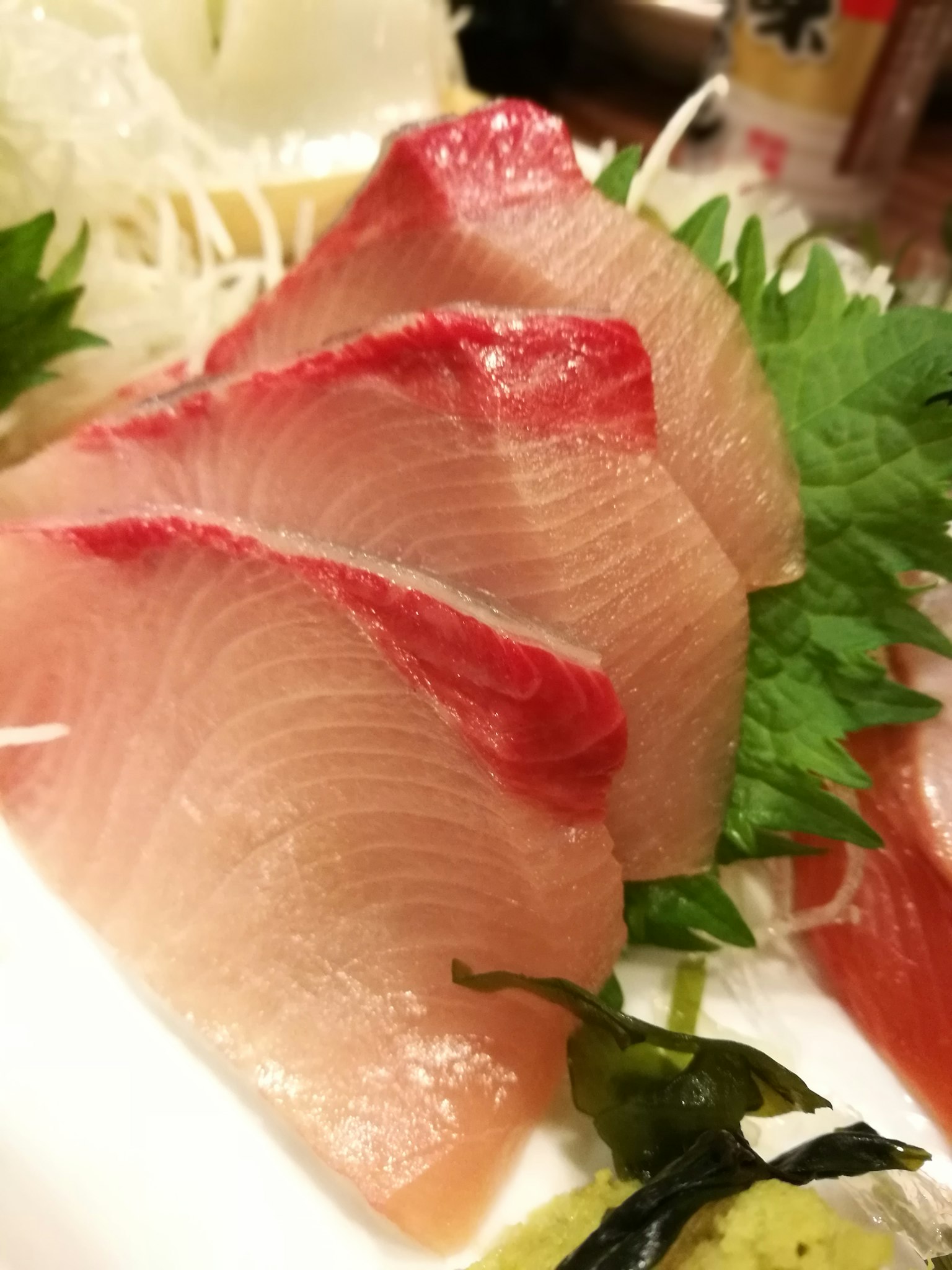 Plato de sashimi fresco con rodajas de pescado rojo y blanco dispuestas ordenadamente