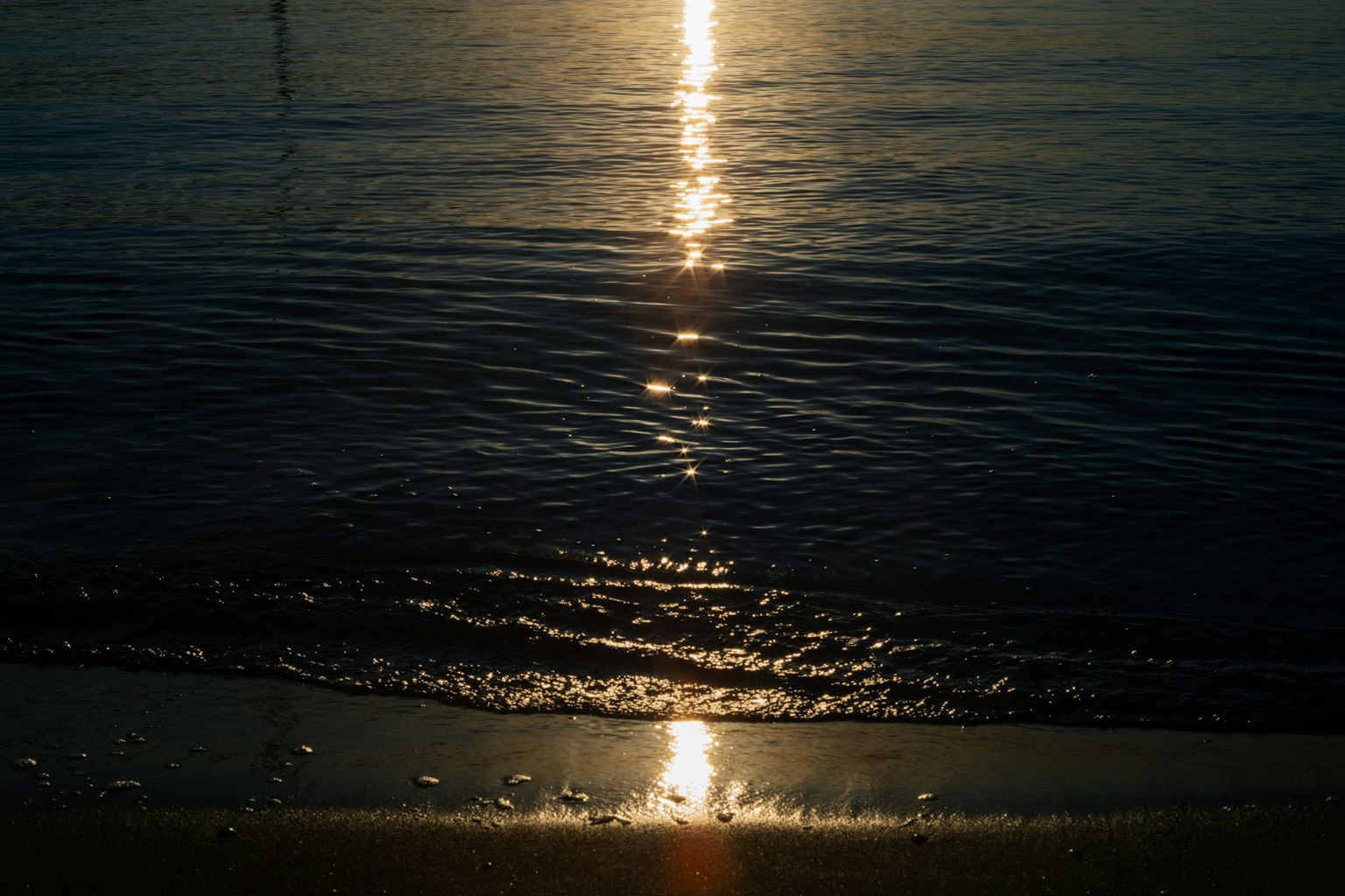 夕陽在平靜的海浪和沙灘上的倒影