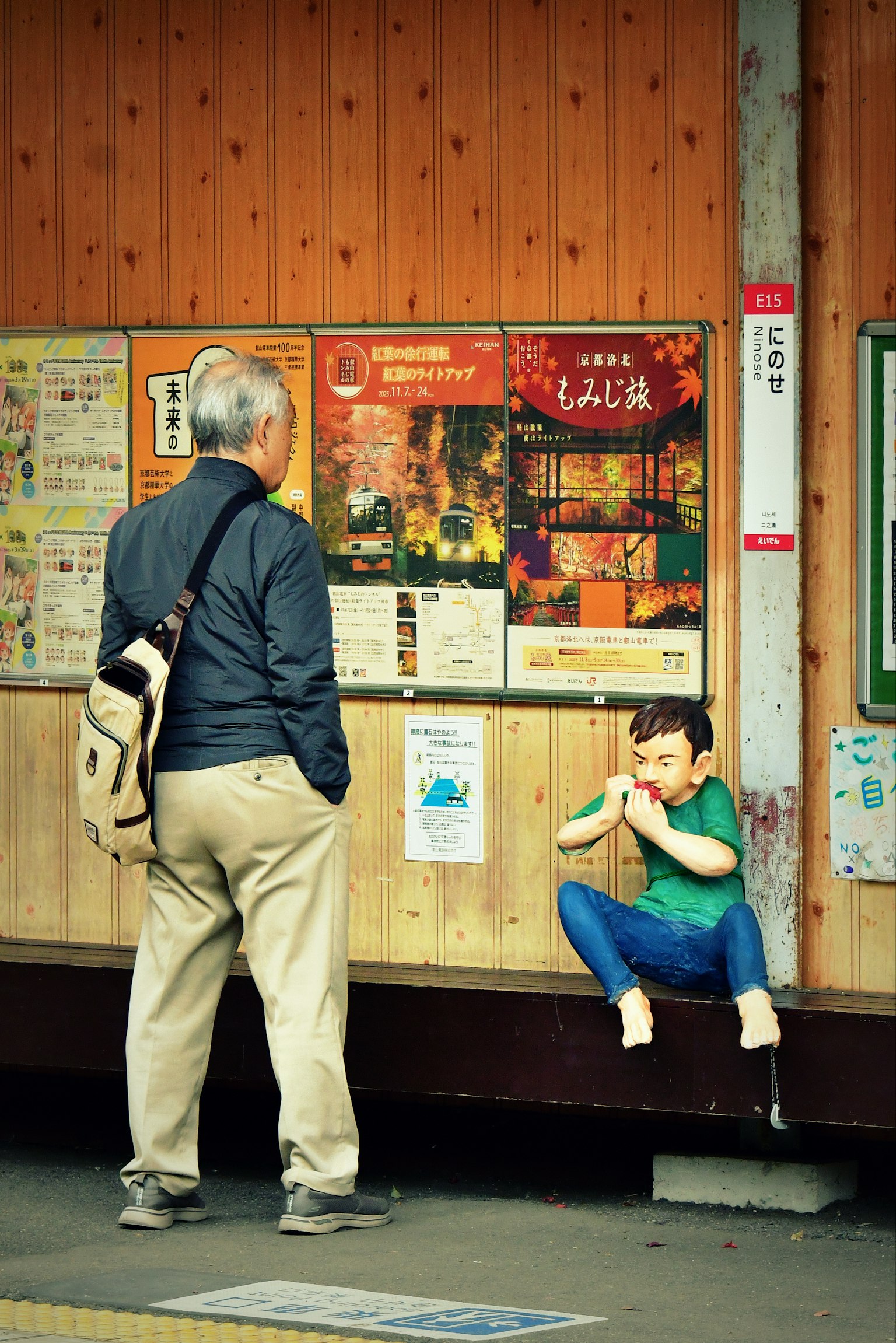 駅の壁に寄りかかる老人と座っている子供の写真