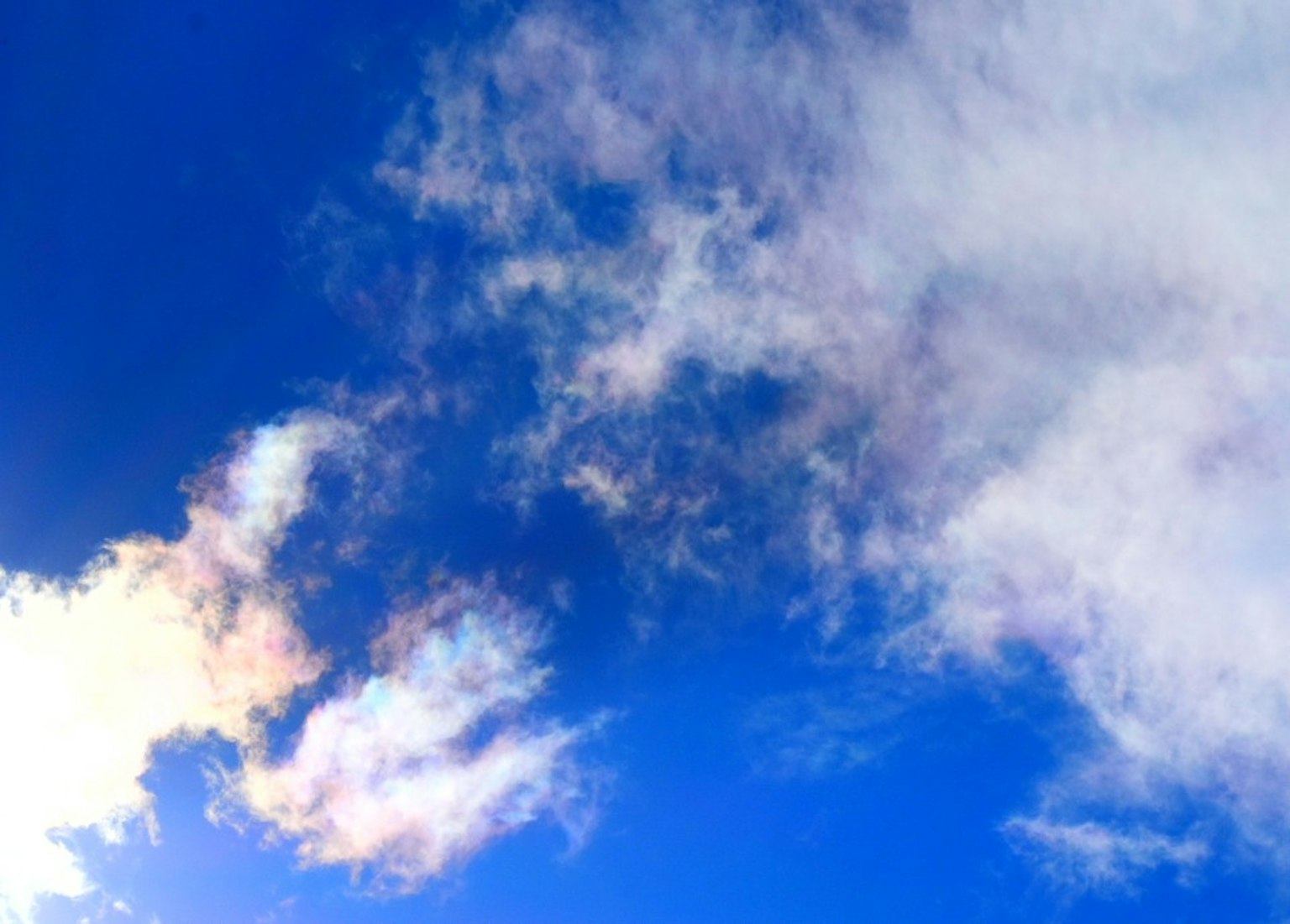Thin clouds reflecting iridescent light against a blue sky