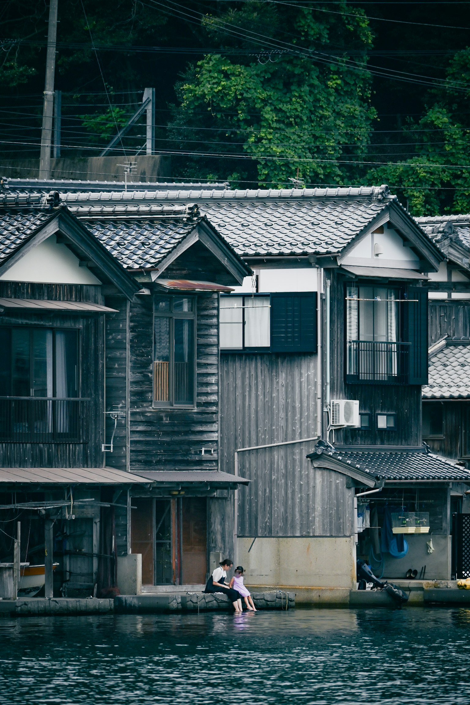 Maisons japonaises traditionnelles au bord de l'eau tranquille avec des résidents