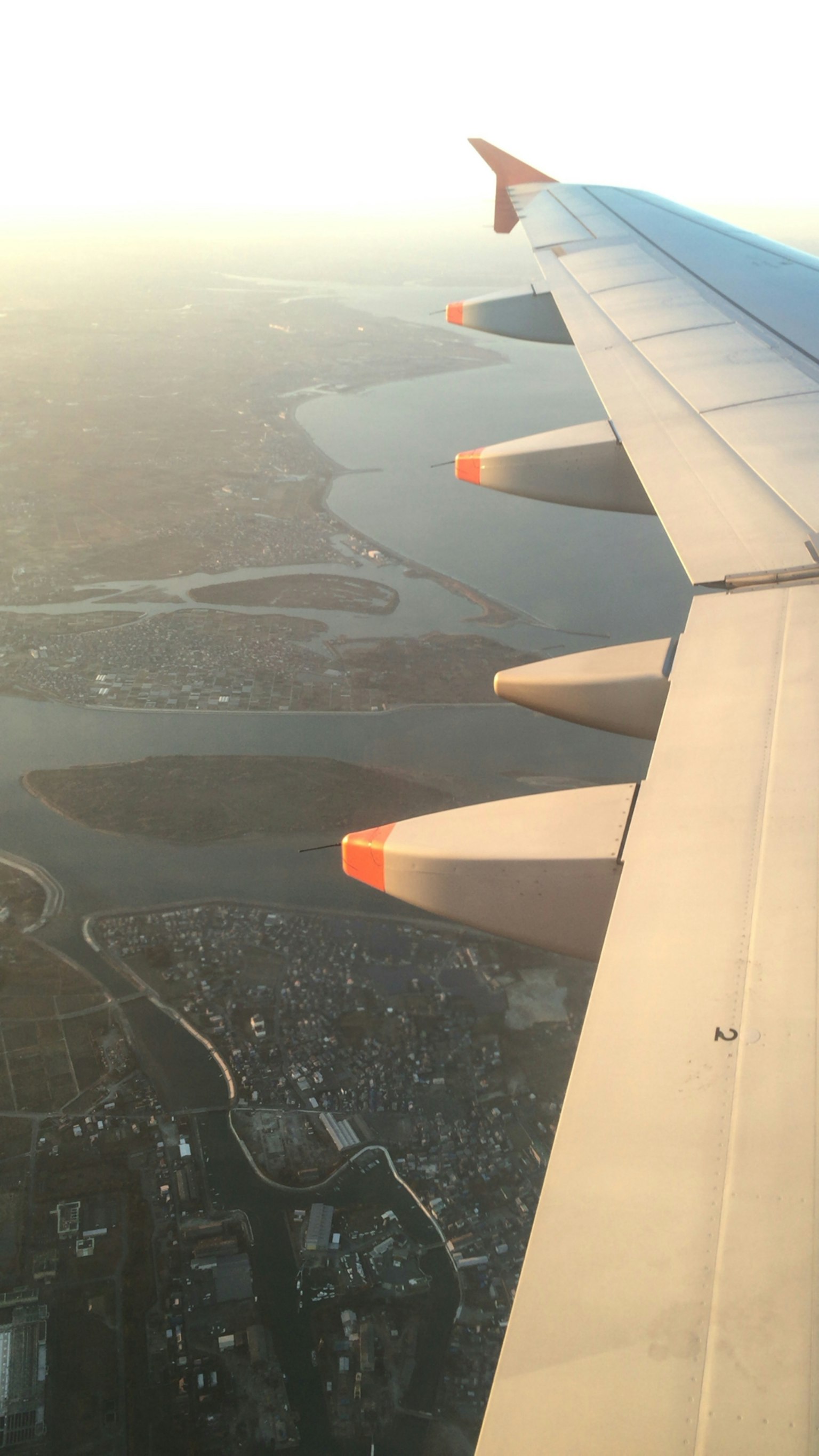 Airplane wing with sunset view over a river and city